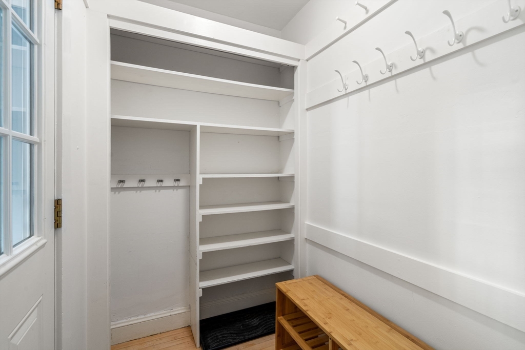 Entryway mudroom with built-in shelves and hooks beside a wooden storage bench.