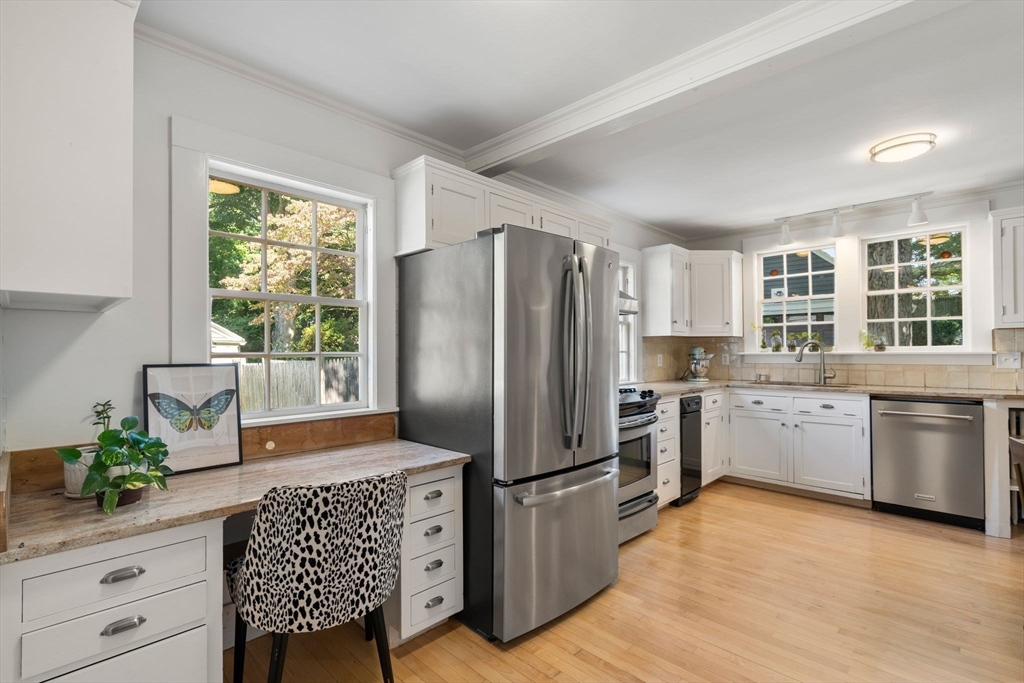 Kitchen with white cabinets, stainless steel appliances, and a window-side desk nook.