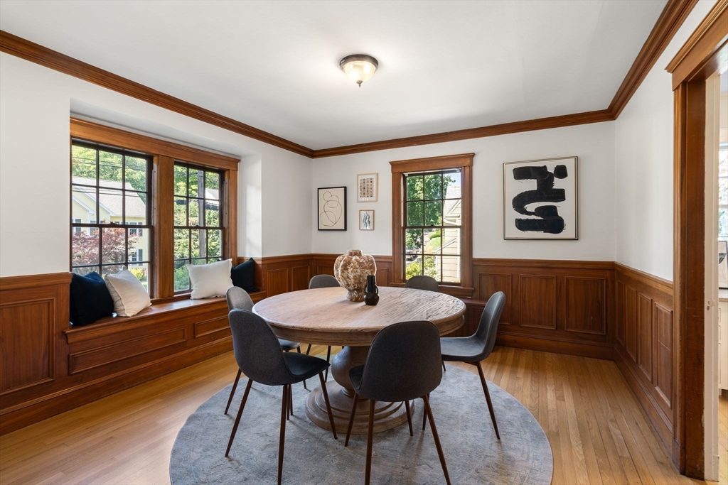 Dining room with a round table, built-in window seat, and rich wood wainscoting.