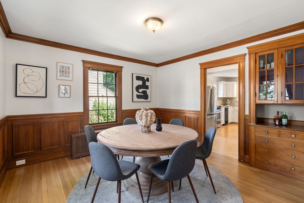 Dining room with a round wooden table, gray chairs, wood-paneled walls, and a built-in cabinet.