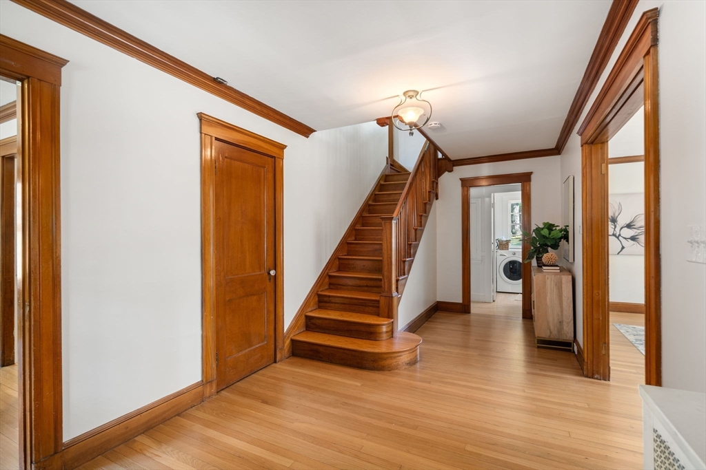 Hallway with a curved wooden staircase, hardwood floors, and rich wood trim.