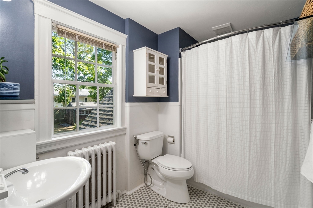 Bathroom with a large window, white fixtures, and a black-and-white mosaic floor.
