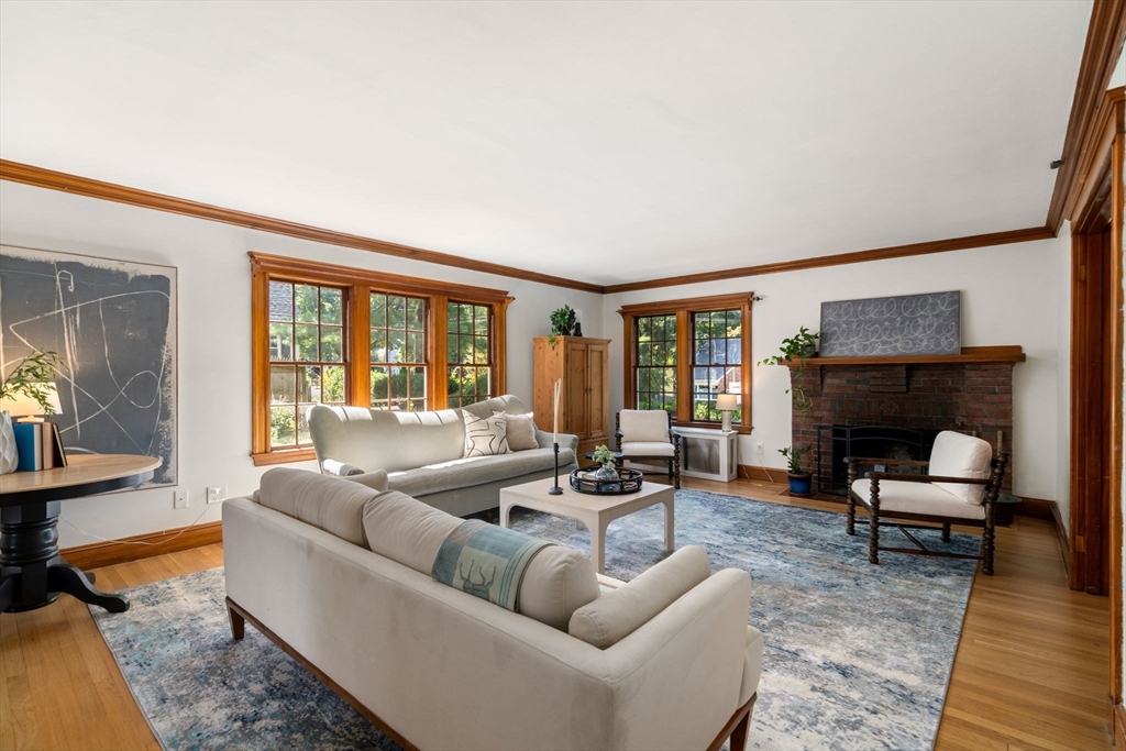 Living room with cream sofas, wood-trimmed windows, and a brick fireplace.