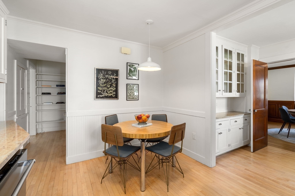 Dining area with a round wood table, four chairs, white built-in cabinets, and hardwood floors.