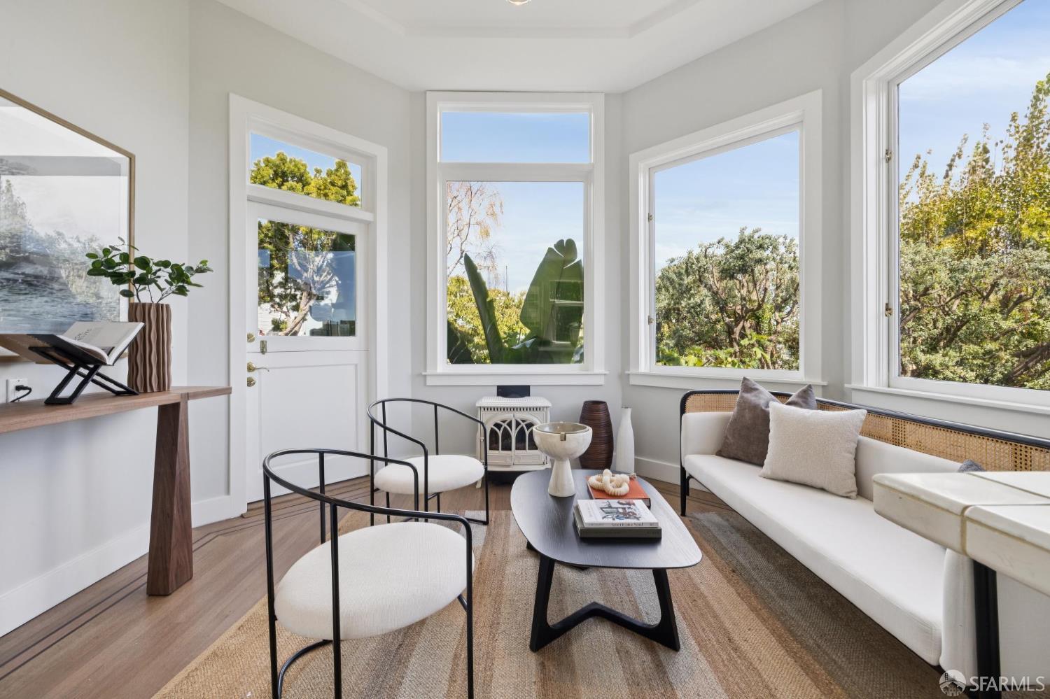 Staged living room with large windows overlooking trees and a white sofa.