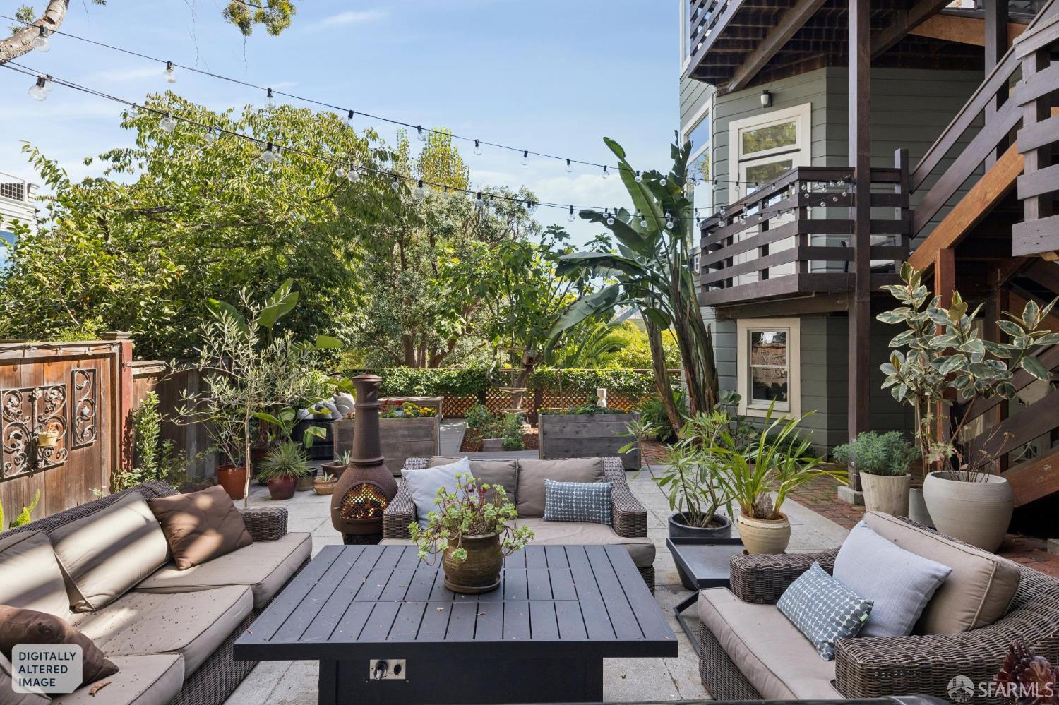 Outdoor patio with wicker seating, a chiminea, raised garden beds, and a wooden deck and stairs.
