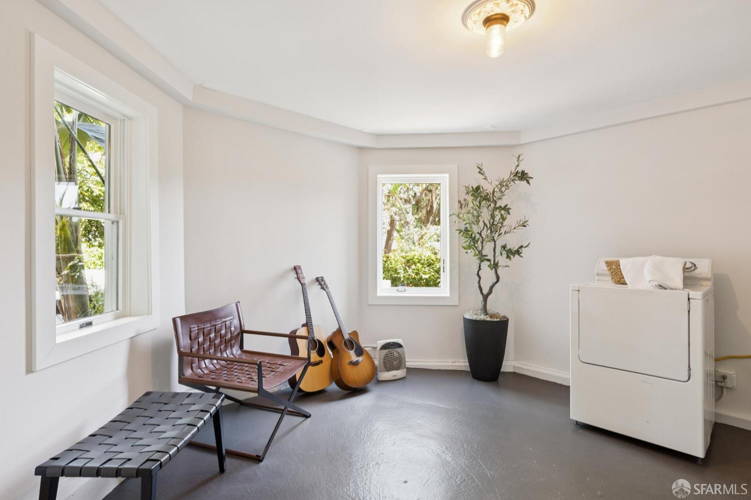 Laundry room with a white appliance, two windows, guitars, and a leather chair.