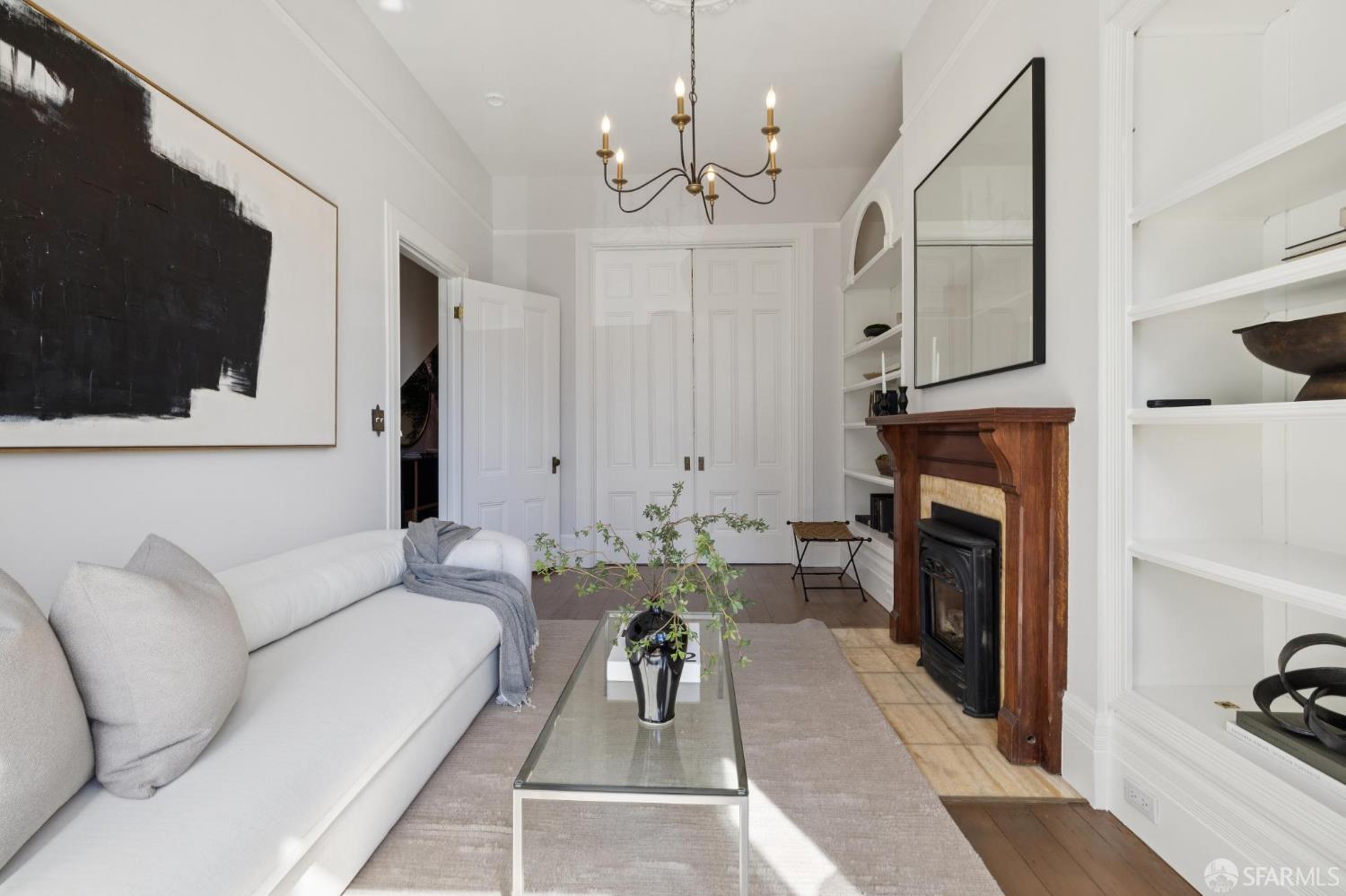 Living room with a white sofa, glass coffee table, and wood fireplace with built-in shelves.