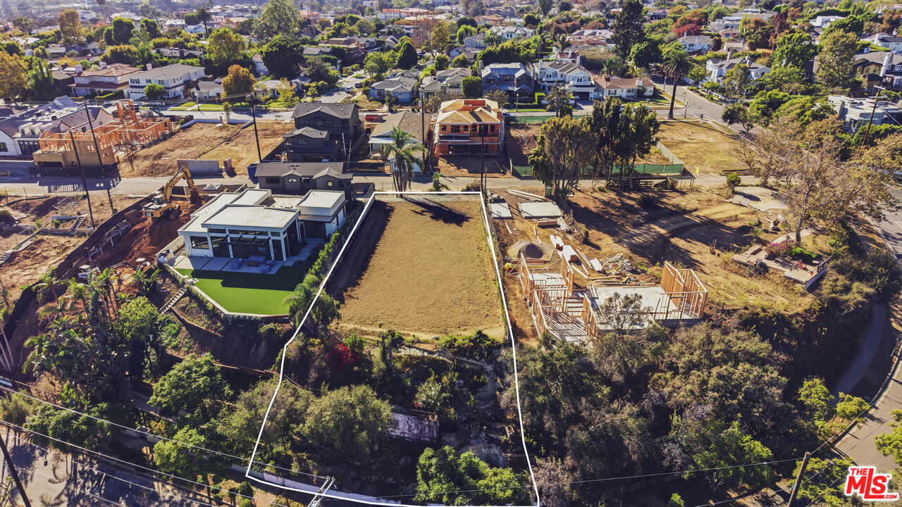Aerial view of an outlined vacant lot surrounded by homes and construction.