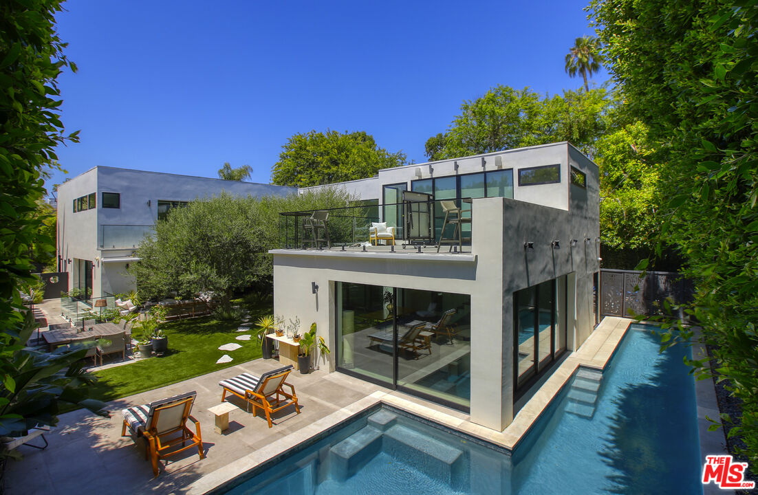 Modern Beverly Hills home with a rooftop terrace and long swimming pool beside the house.