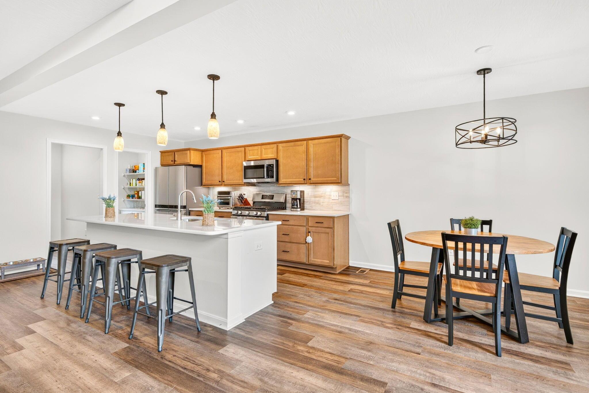 Kitchen with a large island and bar stools beside a round dining table.