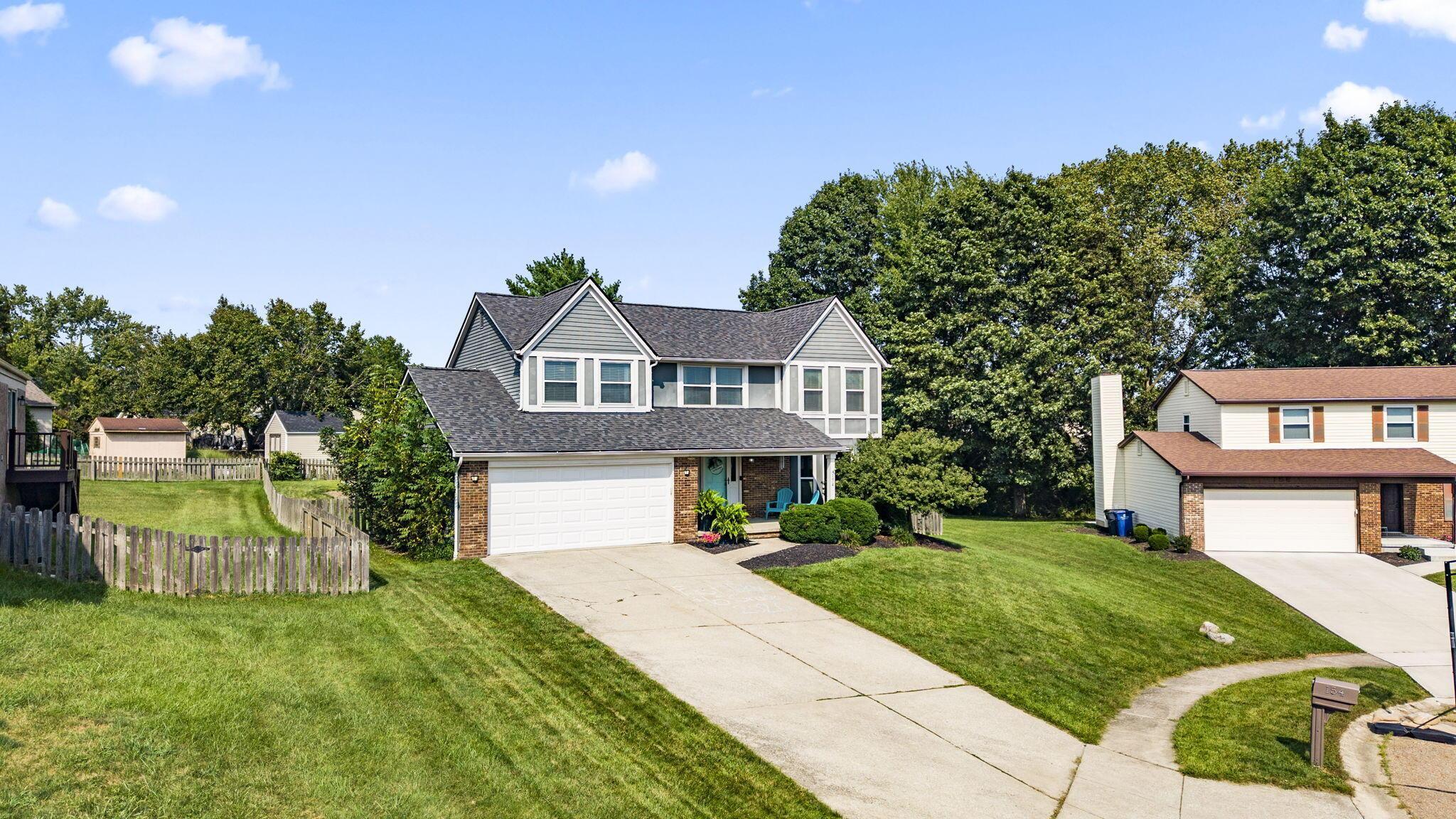 Two-story gray and brick house with a white double garage, front porch, and broad driveway.