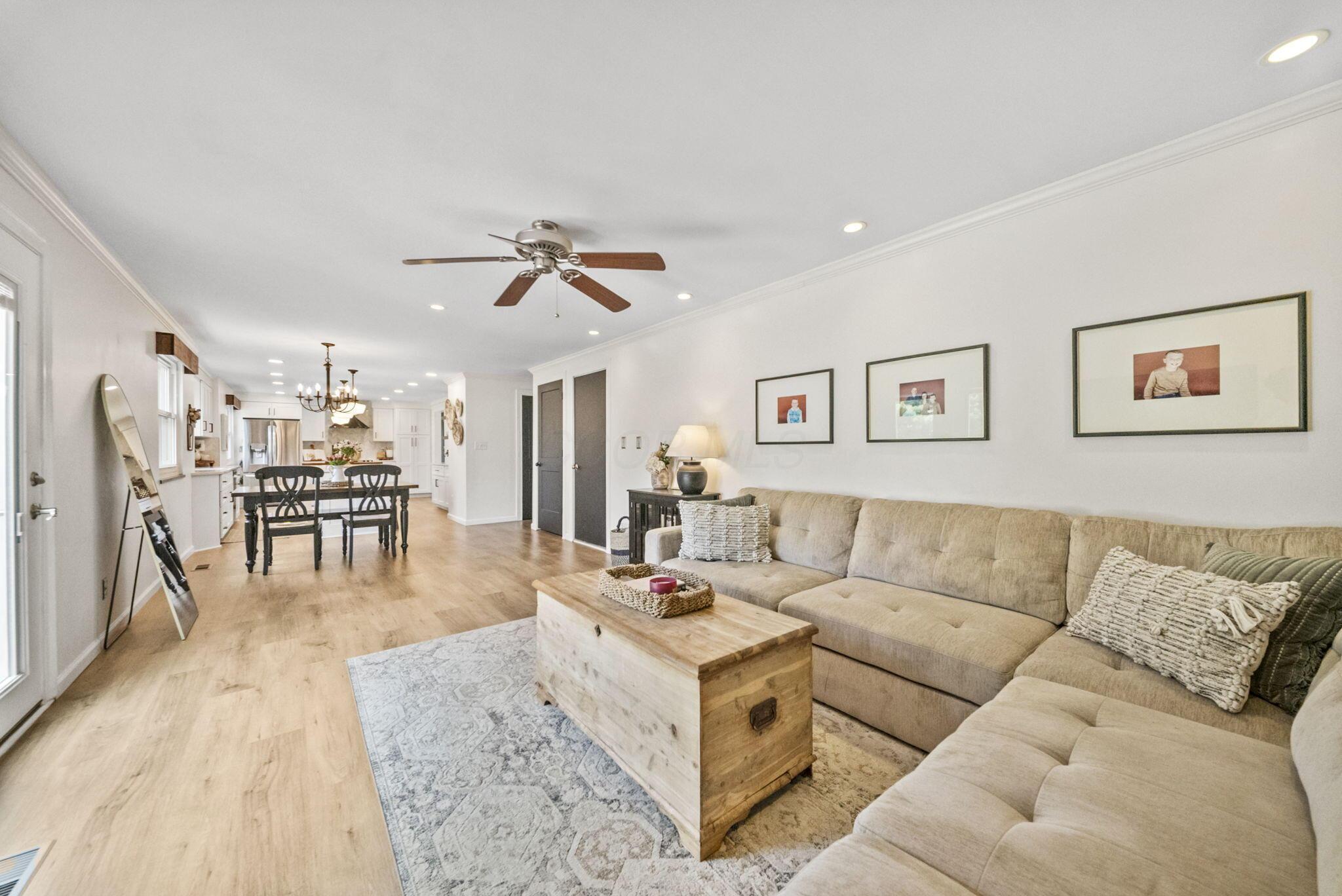 Furnished living room with a beige sectional, wood coffee table, and open dining area and kitchen.