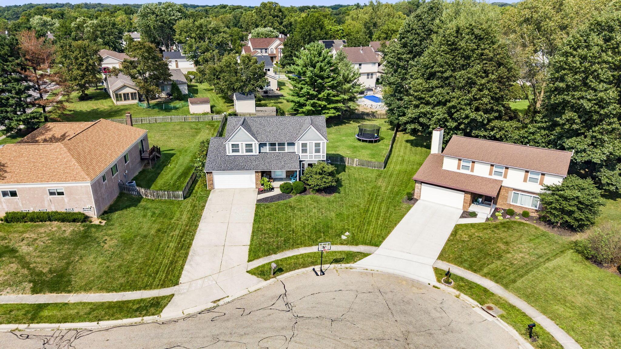 Aerial view of a two-story home with a gray roof, fenced backyard, and neighboring houses.