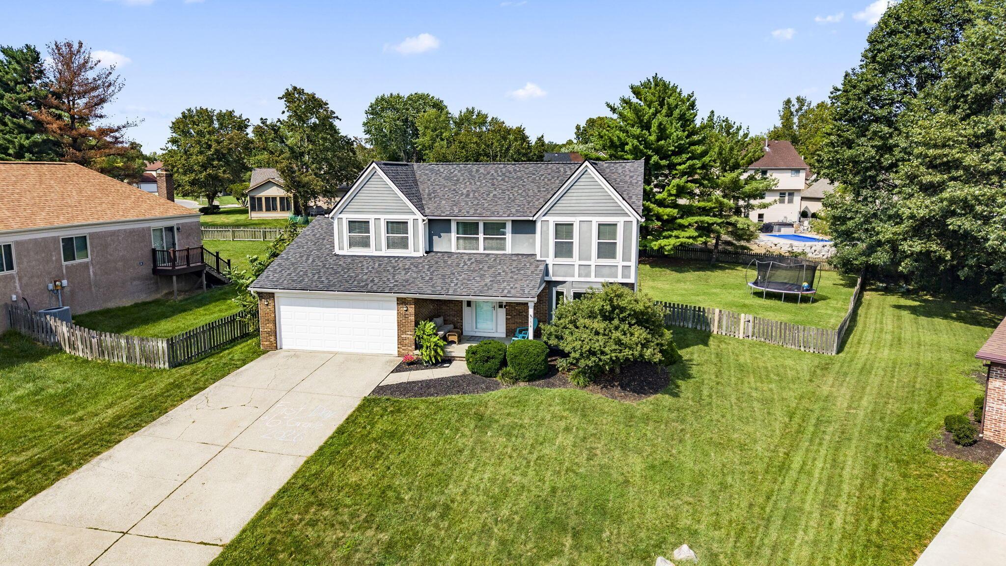 Two-story gray house with an attached garage, landscaped entry, and a wide lawn.