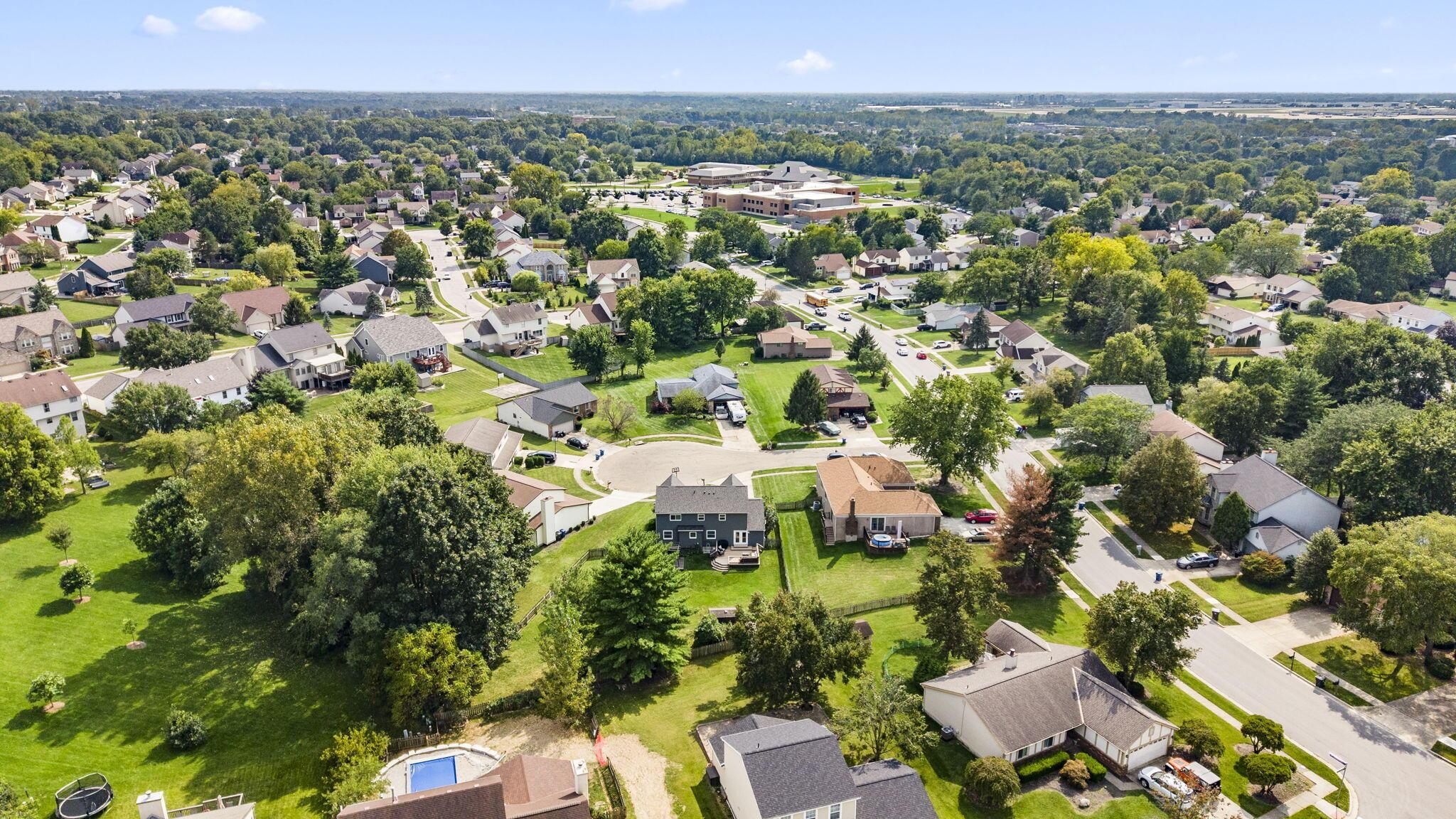 Aerial view of a leafy neighborhood with detached homes, spacious yards, and a cul-de-sac.