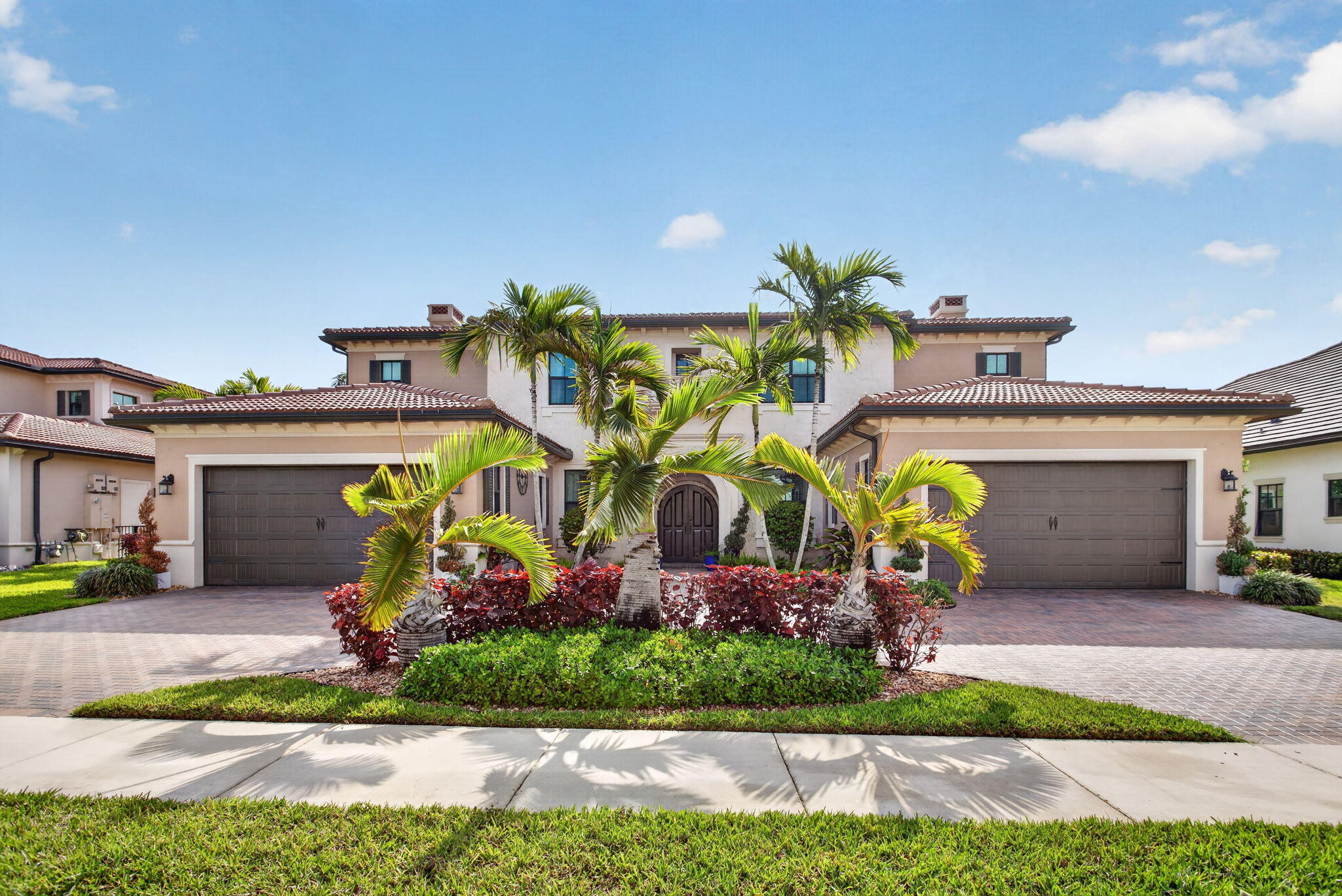 Two-story stucco home with twin garages, palm trees, and landscaped entrance