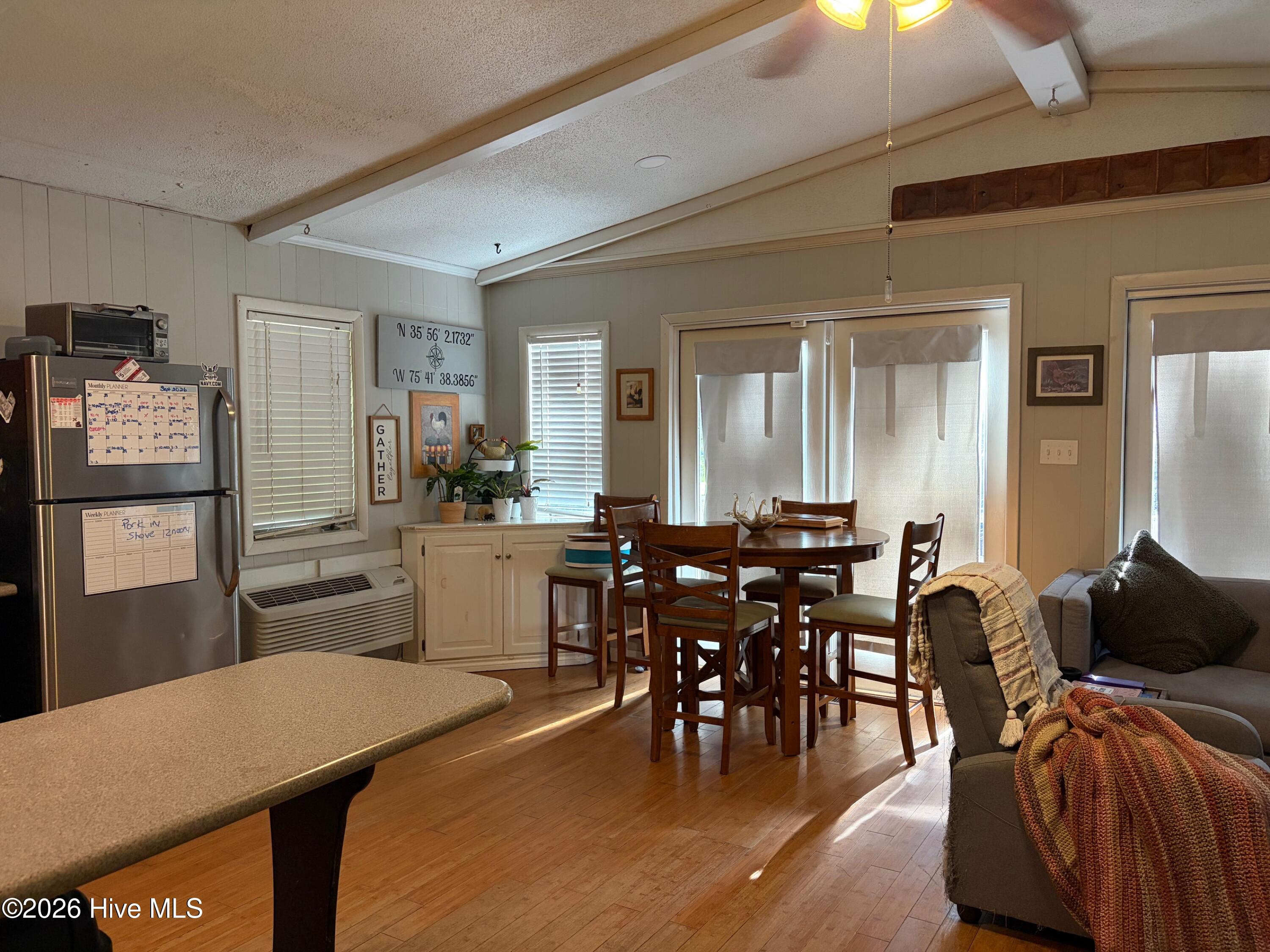 Open-plan kitchen and dining area with a wooden table beside bright sliding glass doors.