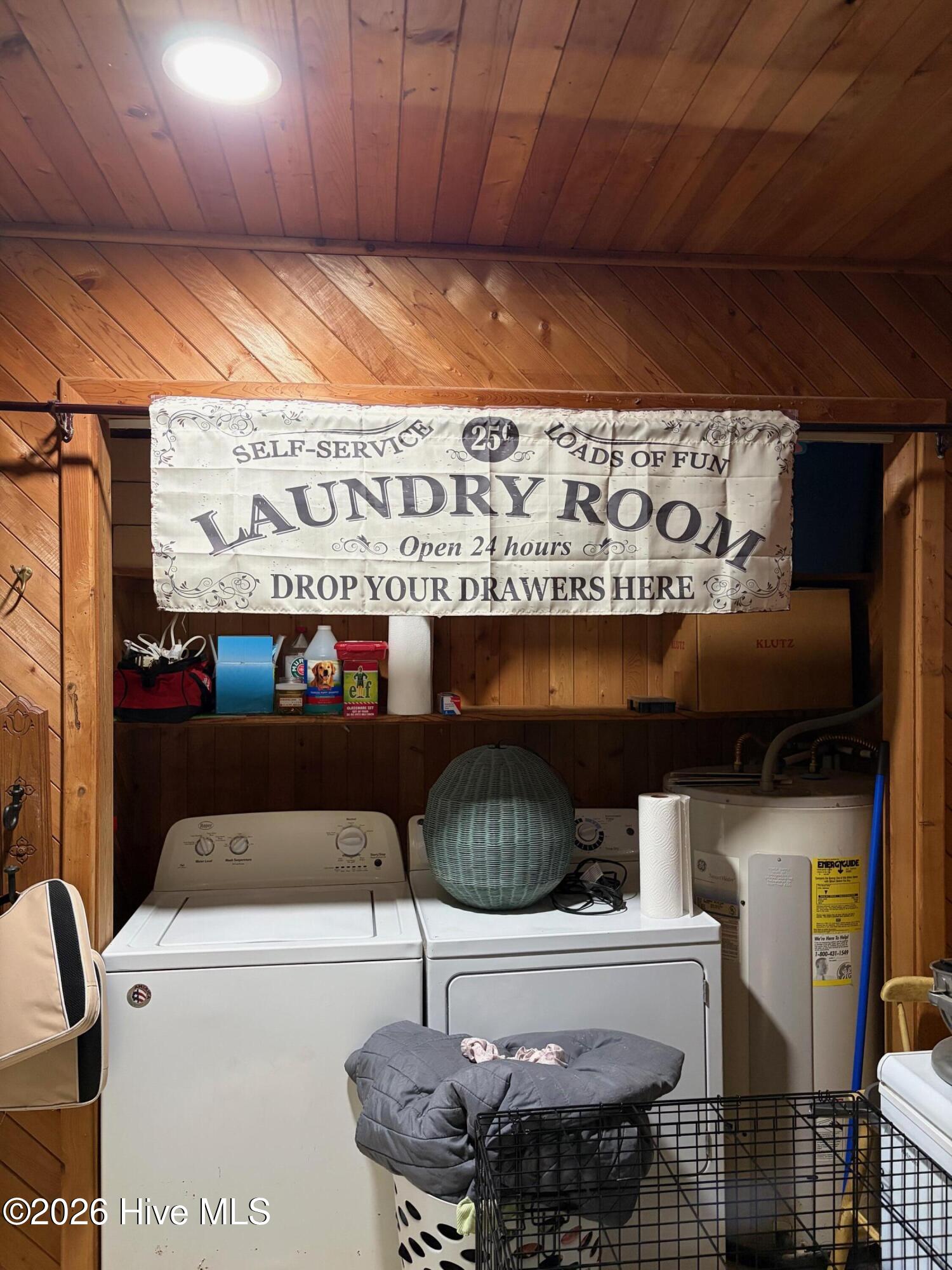 Wood-paneled laundry room with washer, dryer, utility sink, and a humorous banner above the appliances.