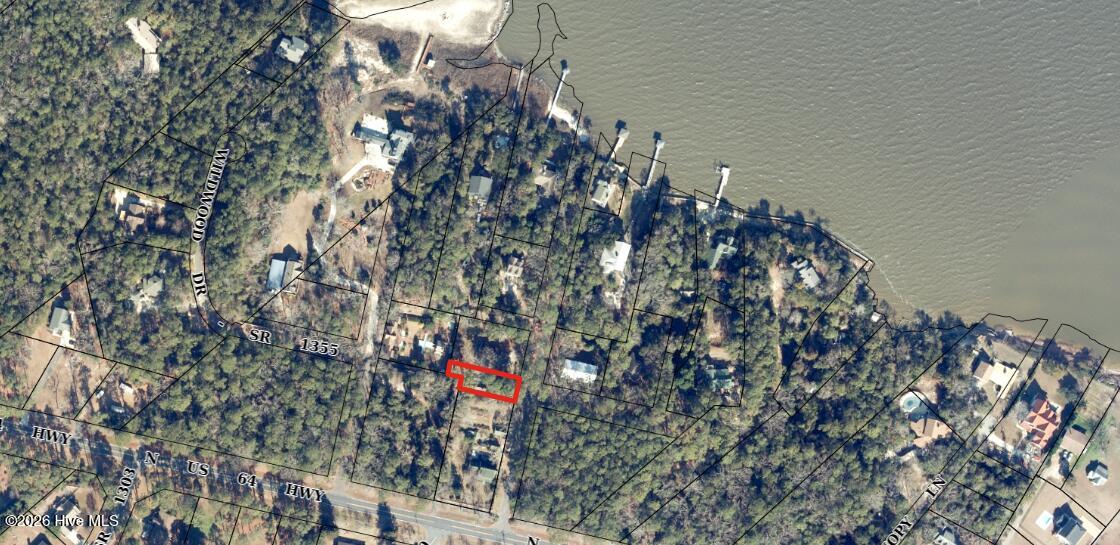 Aerial view of the wooded shoreline parcel outlined in red, with nearby roads and homes.