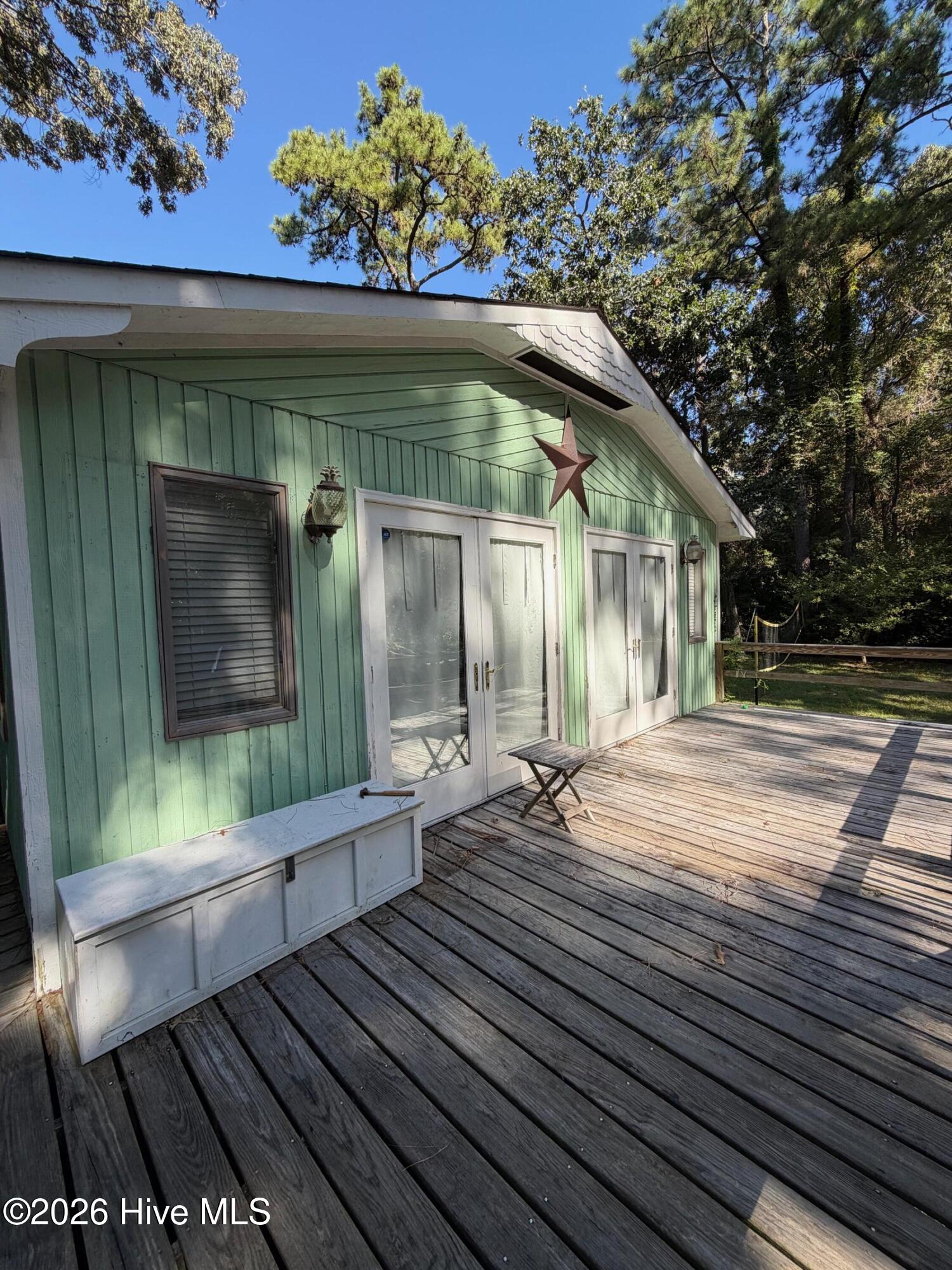 Mint-green home exterior with glass doors, a large metal star, and a spacious wooden deck.