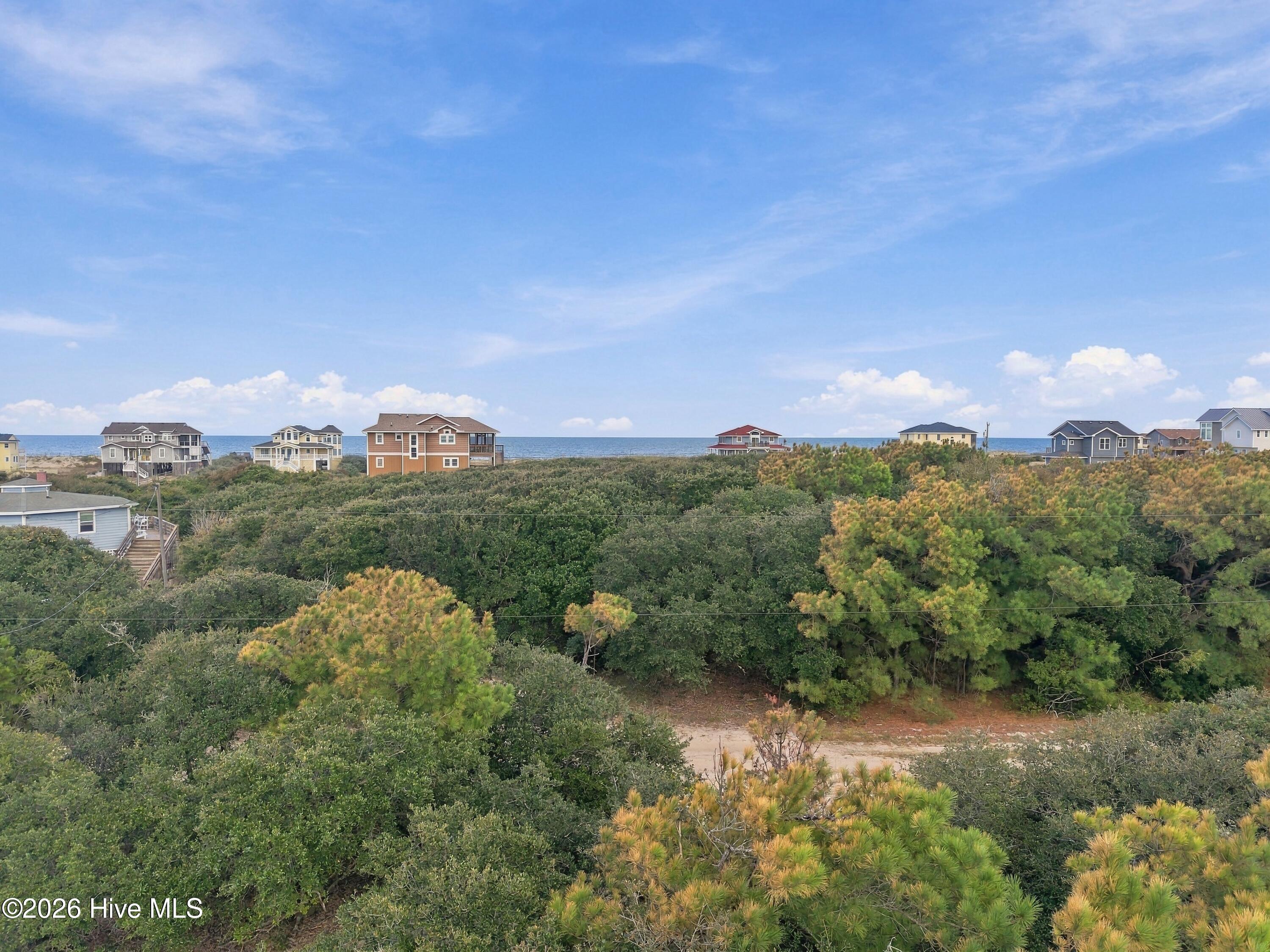 Aerial view across coastal dune vegetation toward beach houses and the Atlantic.