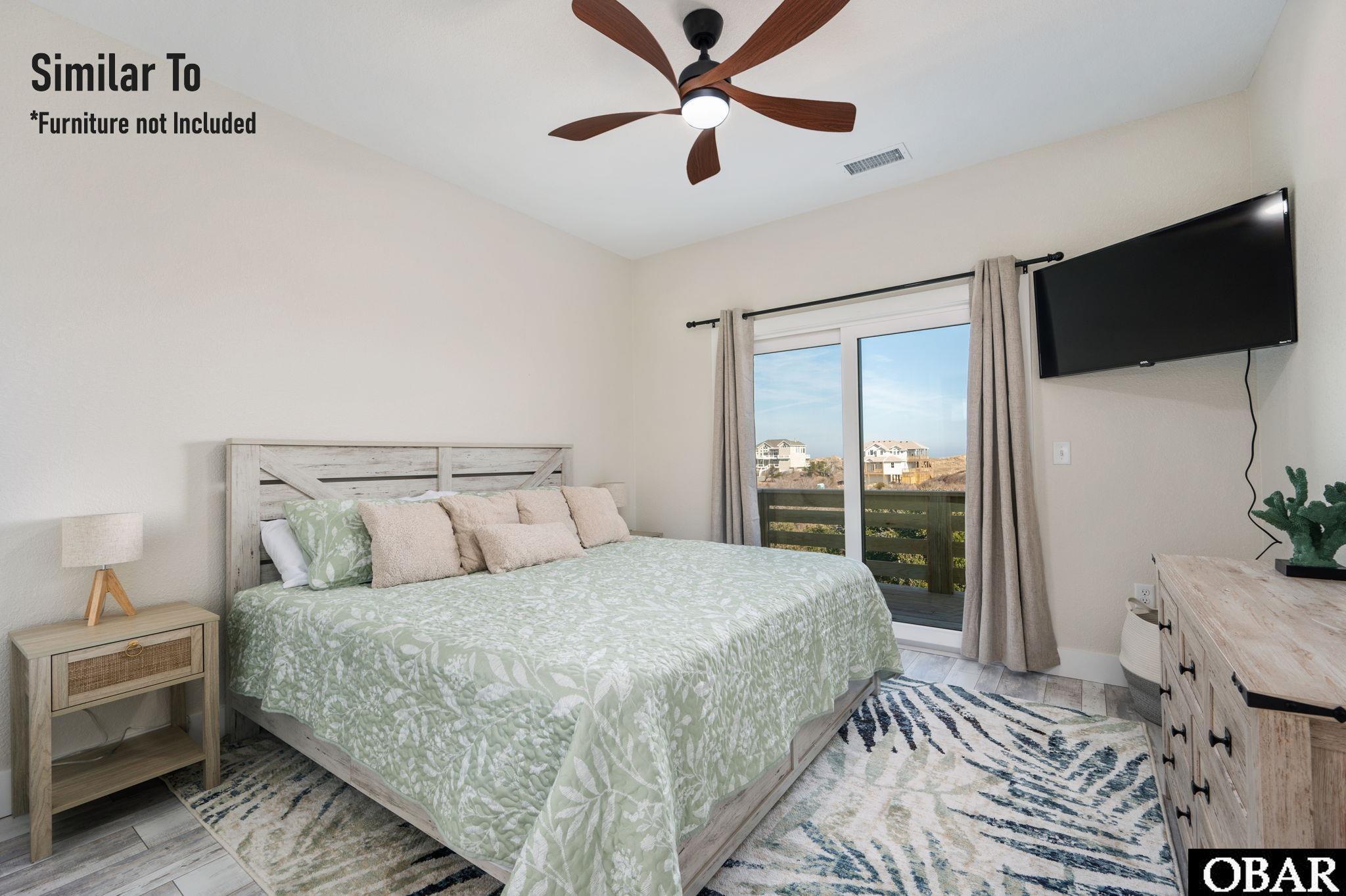 Bedroom with pale green patterned bedding, a sliding glass door, and a wood-bladed ceiling fan.