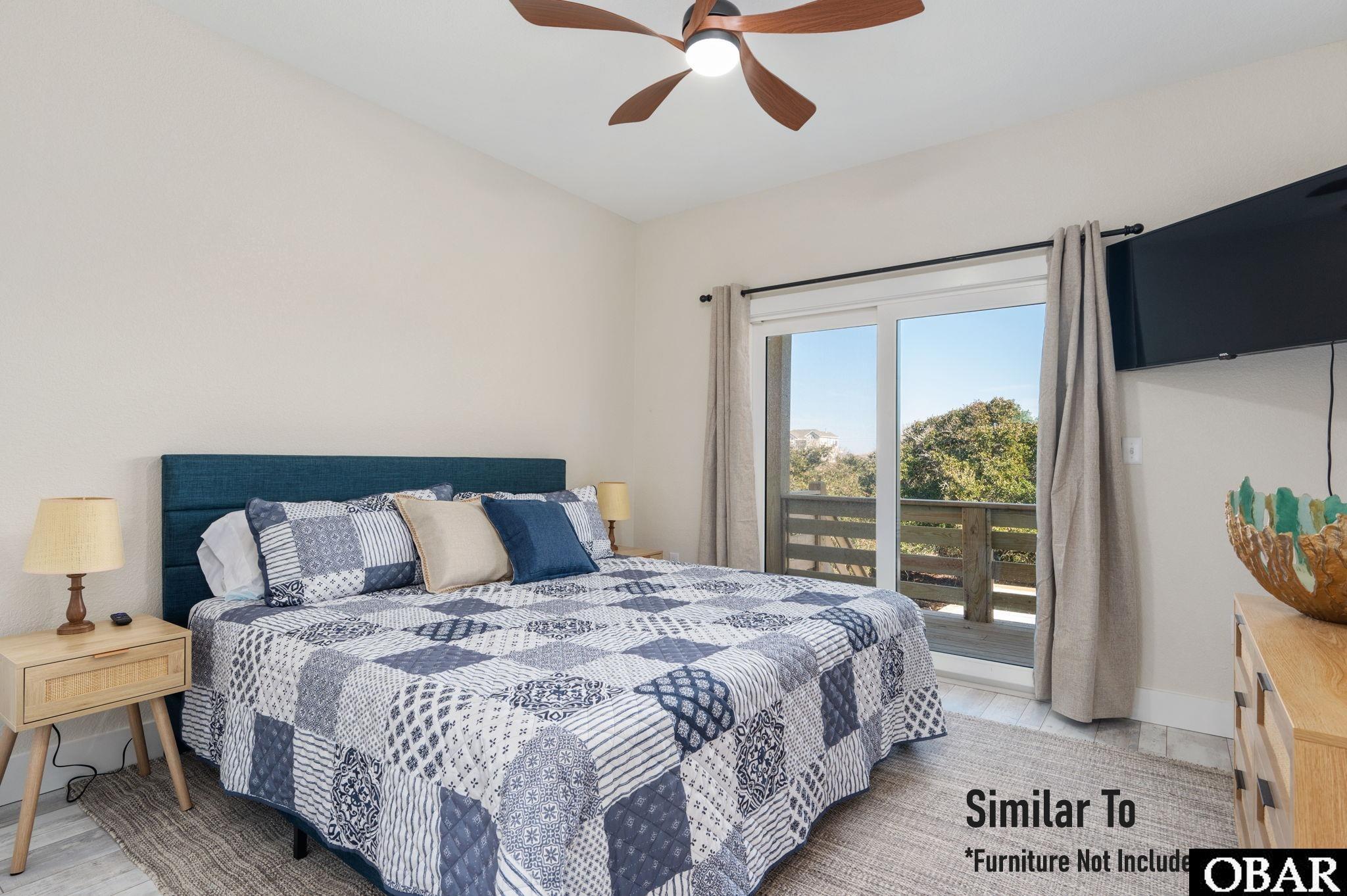 Bedroom with blue-and-white patchwork bedding and sliding doors opening to a balcony.