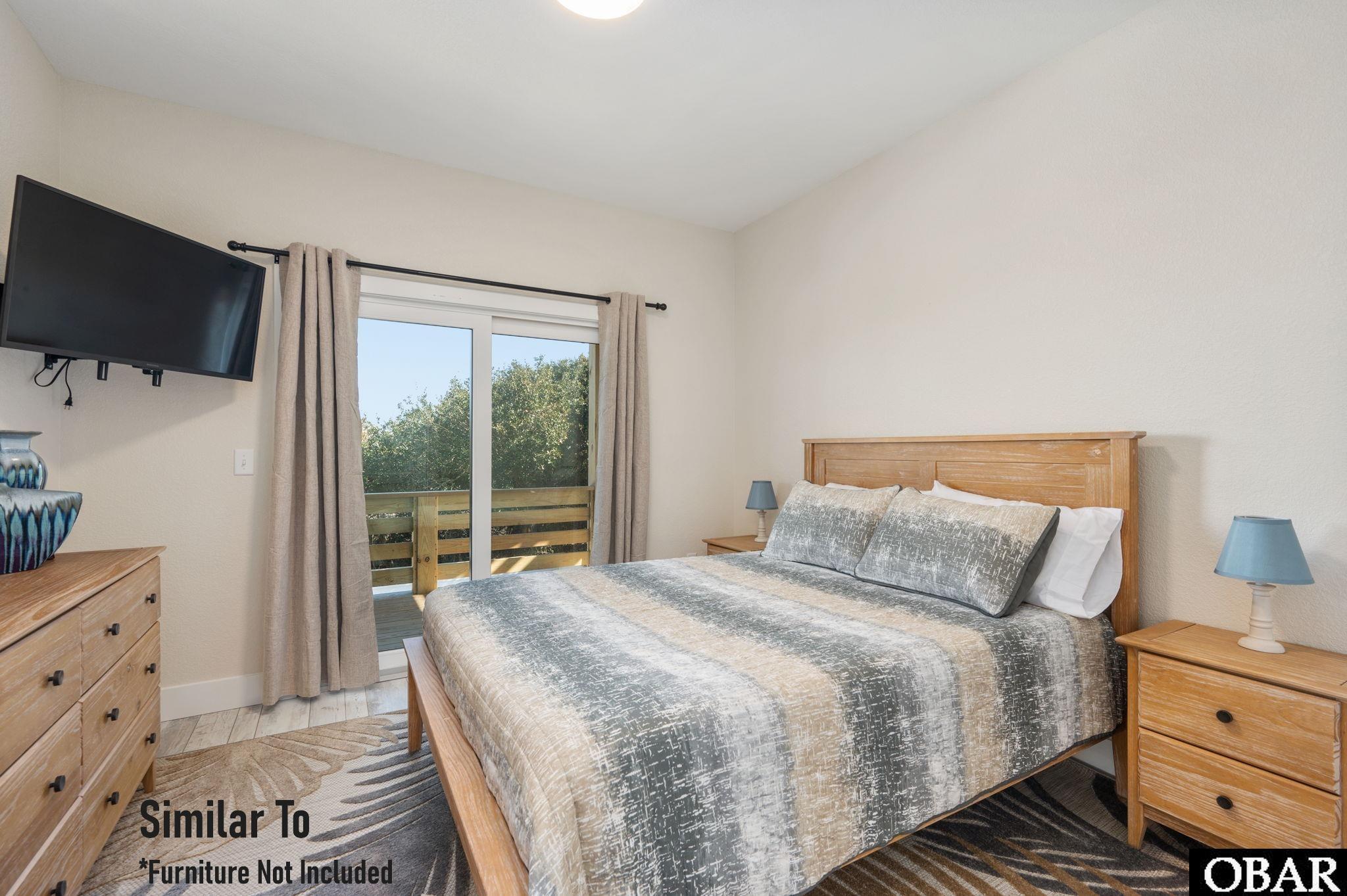 Bedroom with a wooden bed and sliding glass doors opening onto a deck.