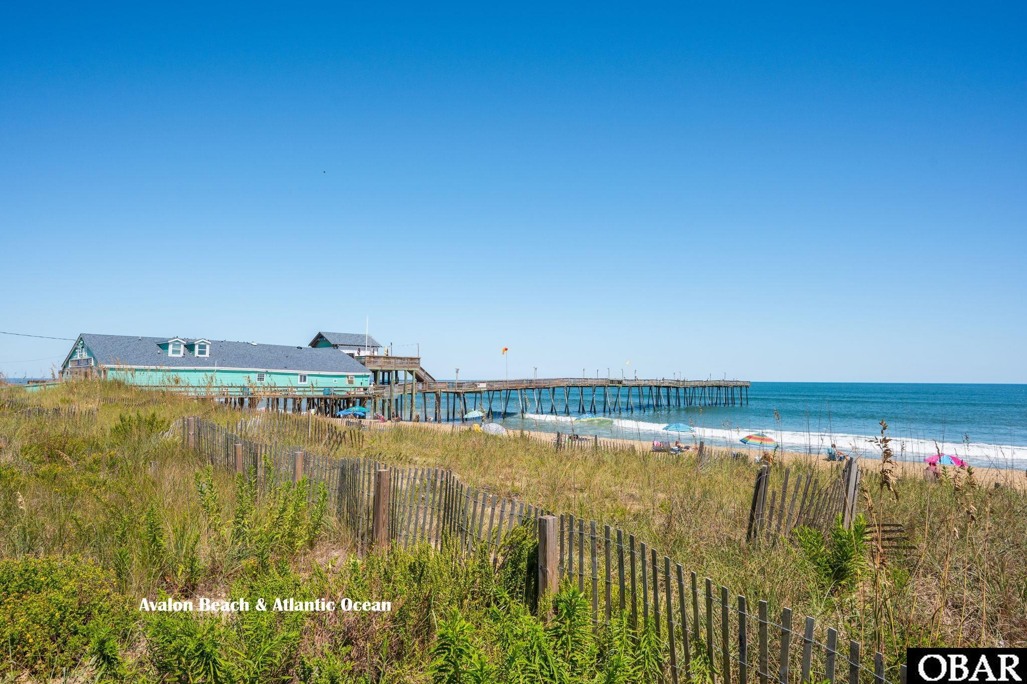 Avalon Beach and the Atlantic Ocean, with a long pier extending over the water beyond grassy dunes.