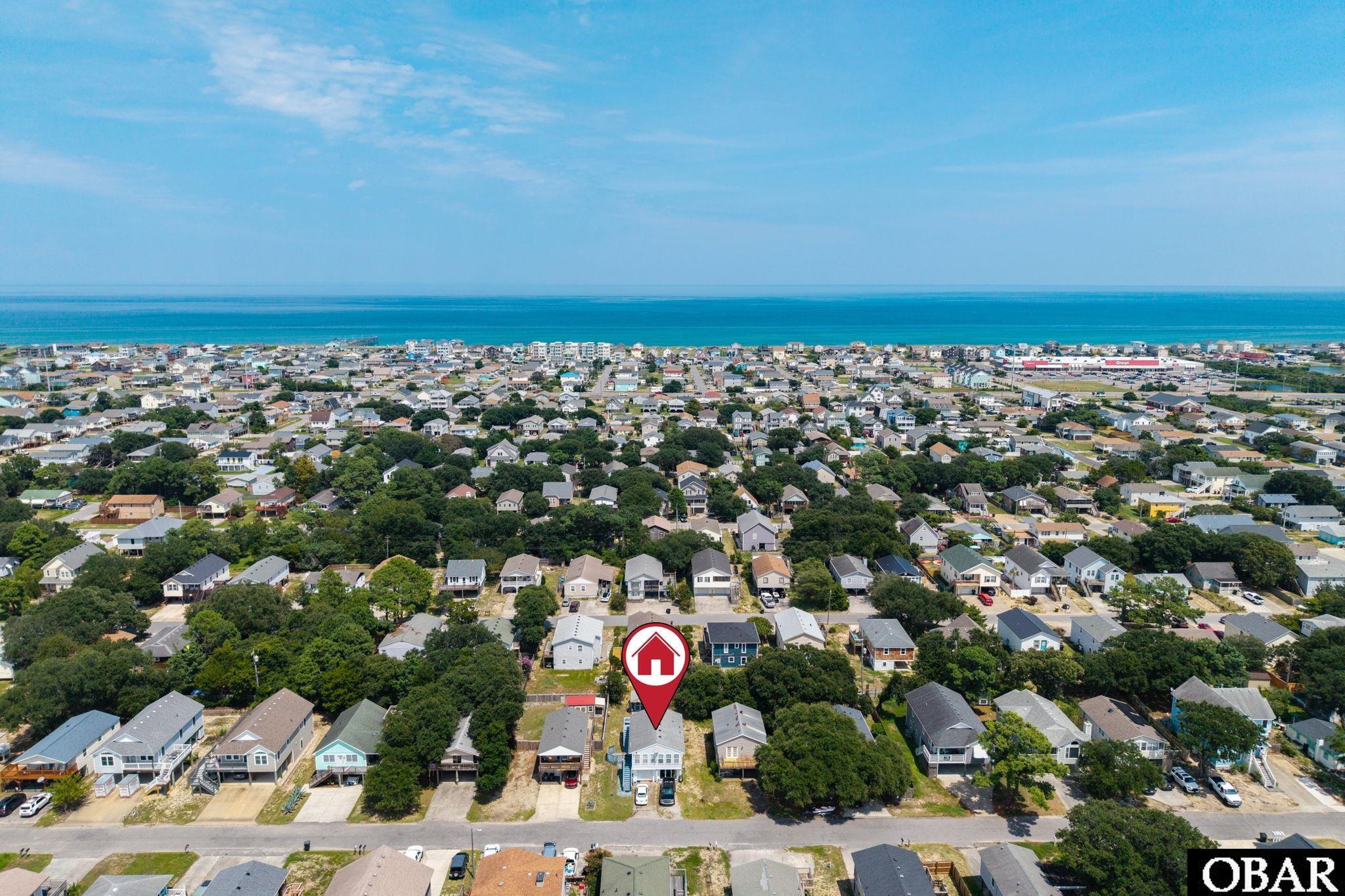 Aerial view of a coastal neighborhood and ocean, with the listed home marked.