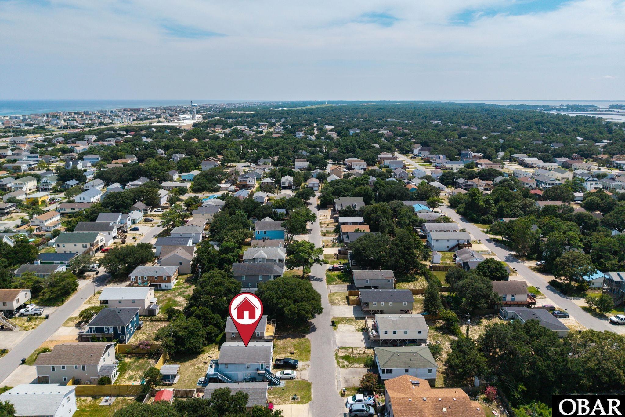 Aerial view of a coastal neighborhood, with the listed home marked near the foreground.