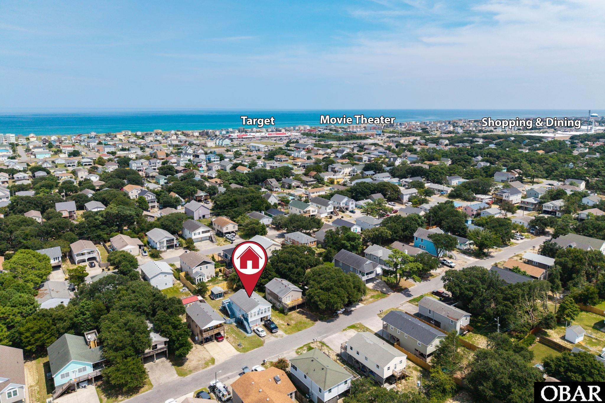 Aerial view of a coastal neighborhood, with a marker identifying a home and the ocean beyond.