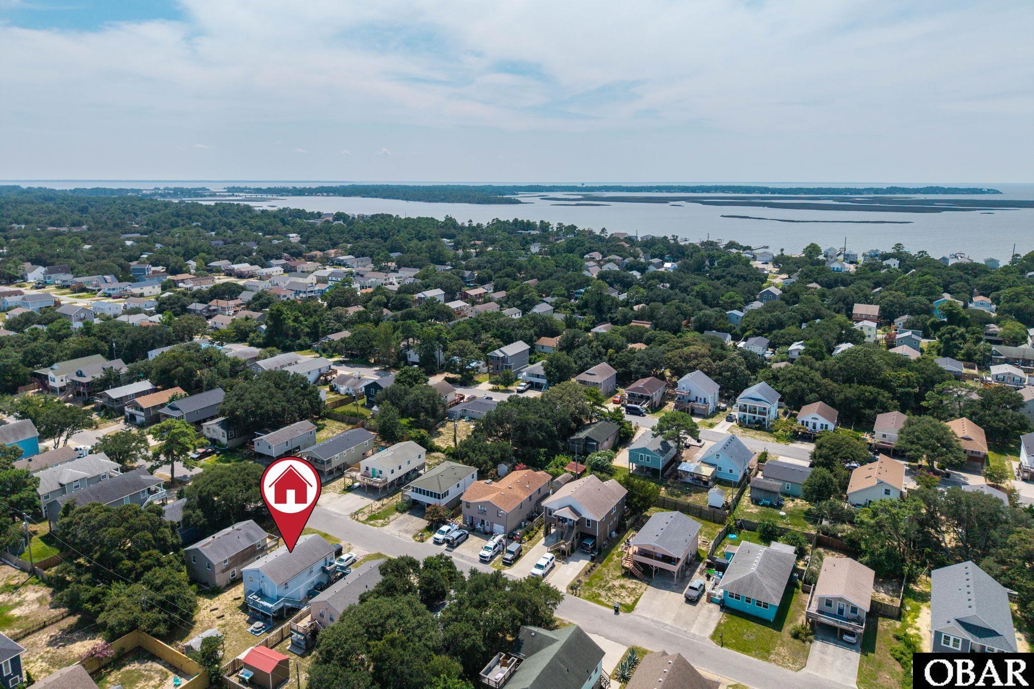 Aerial view of a coastal neighborhood, with the marked property near the water.
