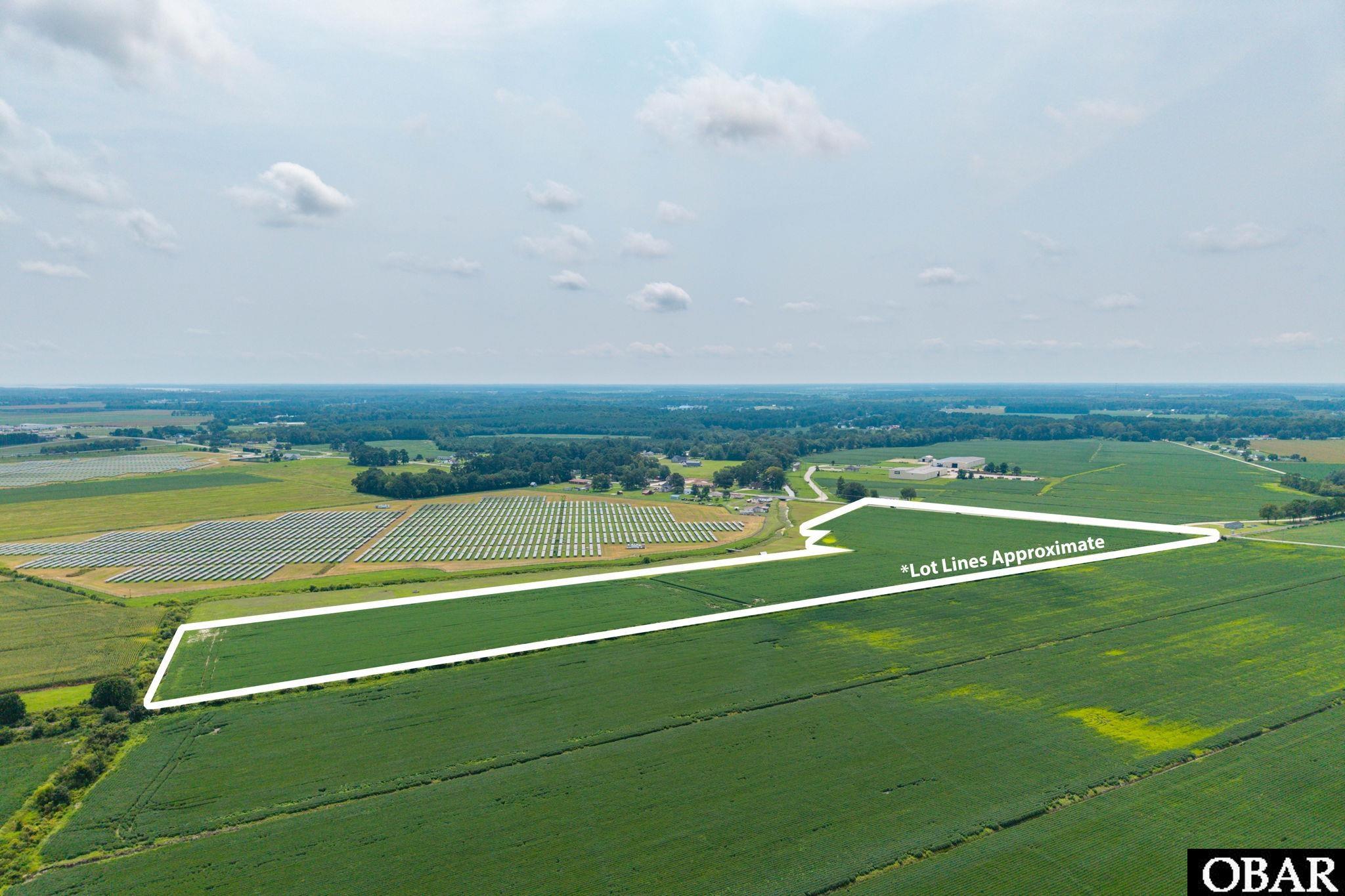 Aerial view of green farmland parcel outlined in white, with solar panels on neighboring fields.