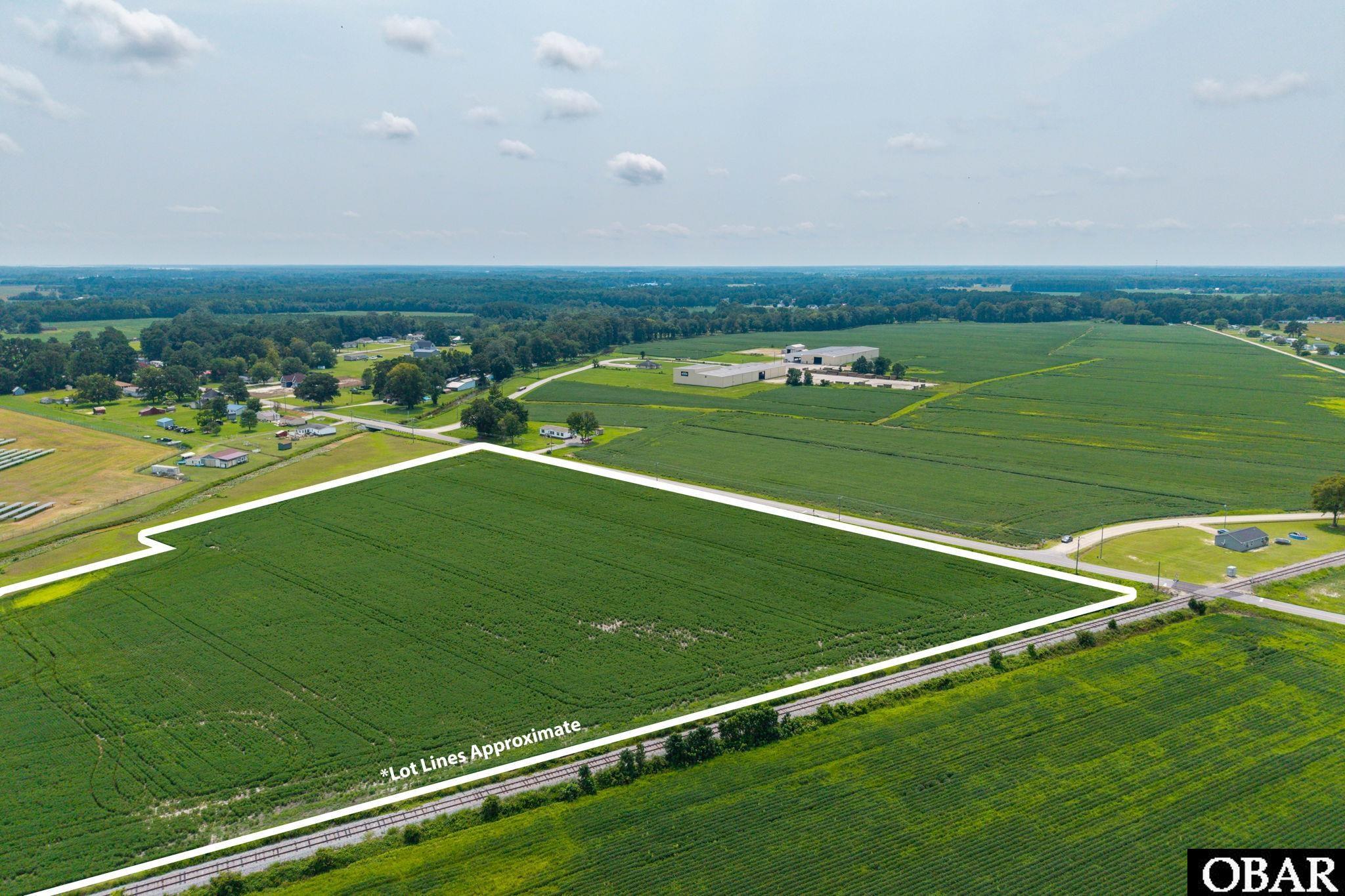Aerial view of green farmland outlined beside railroad tracks, with approximate lot lines marked in white.