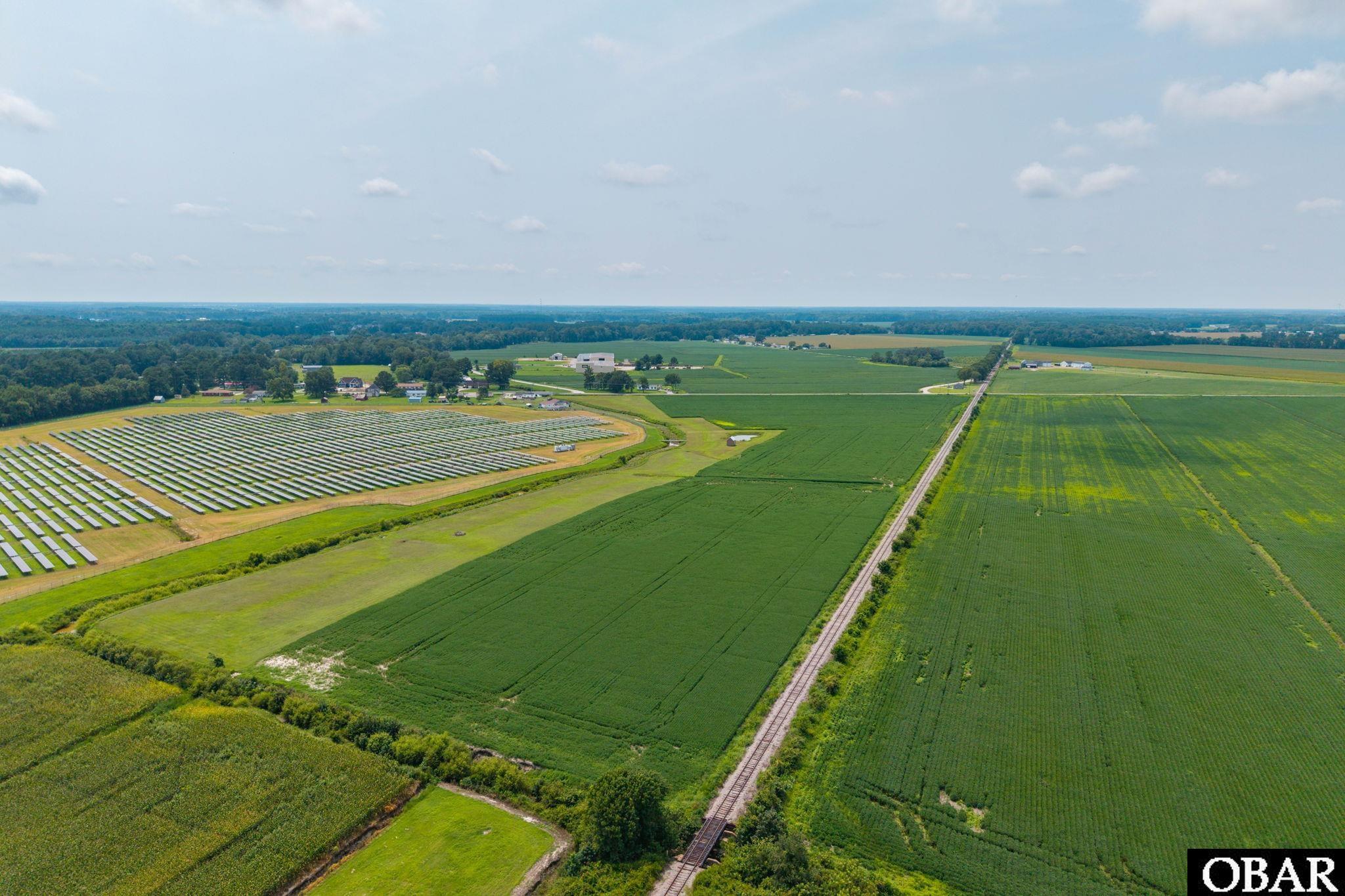 Aerial farmland with a large solar panel array and railroad tracks.