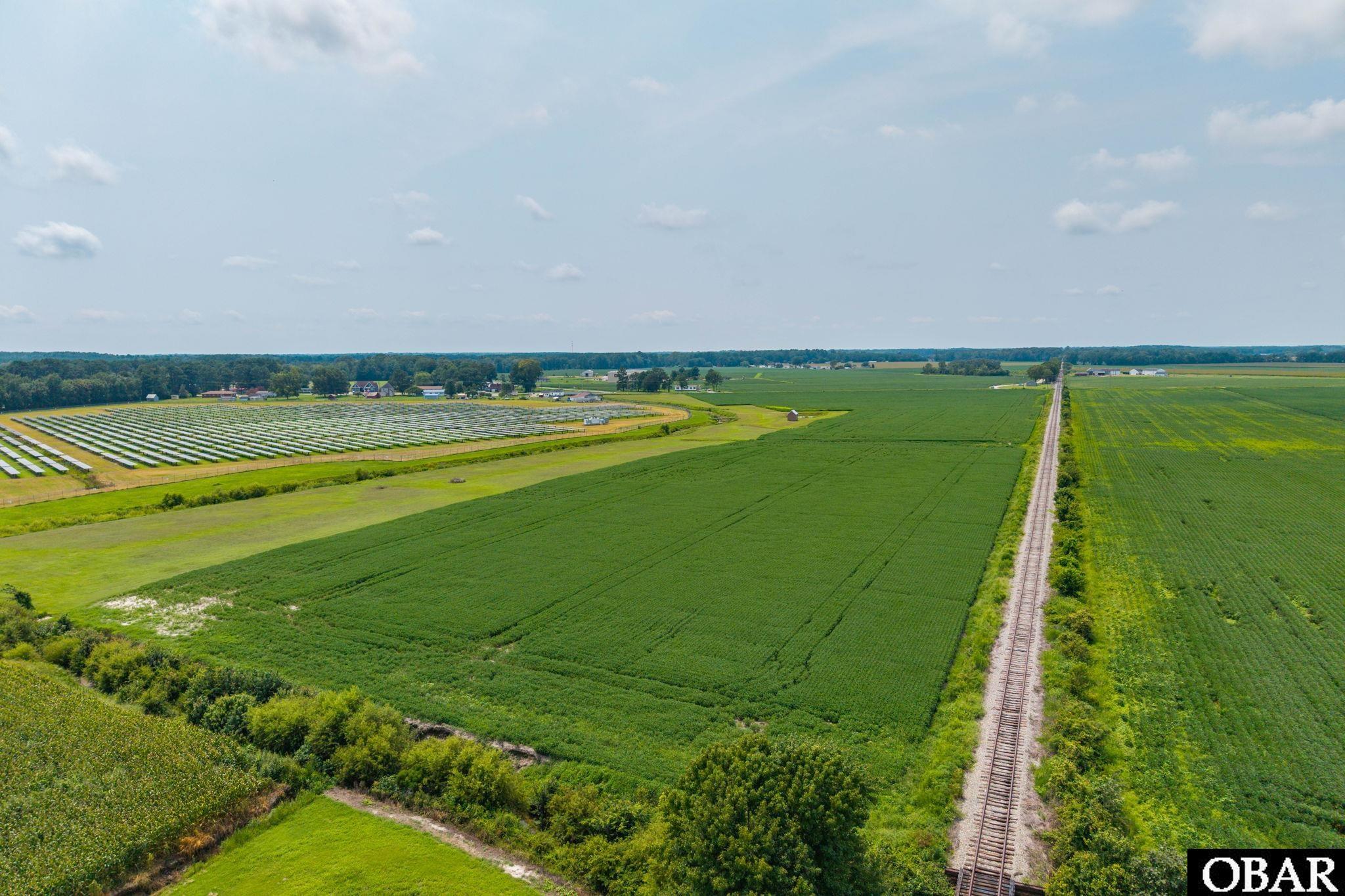 Aerial farmland with a railroad track and a solar panel array.