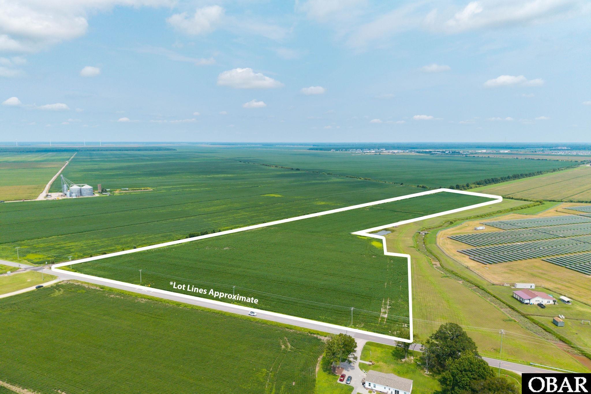 Aerial view of expansive farmland outlined with approximate lot lines beside a road and solar array.