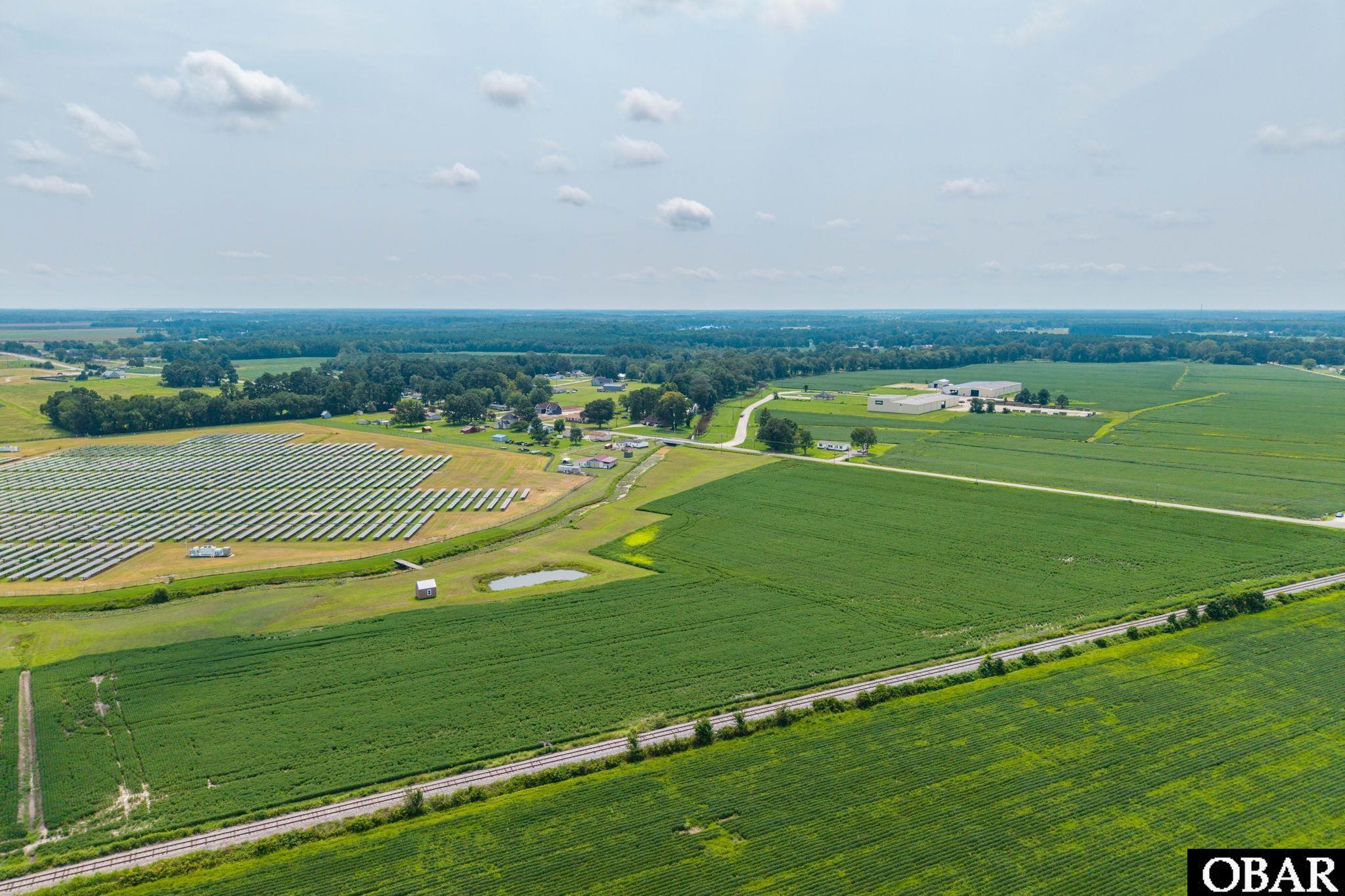 Aerial view of agricultural fields with a solar panel array and railroad tracks.