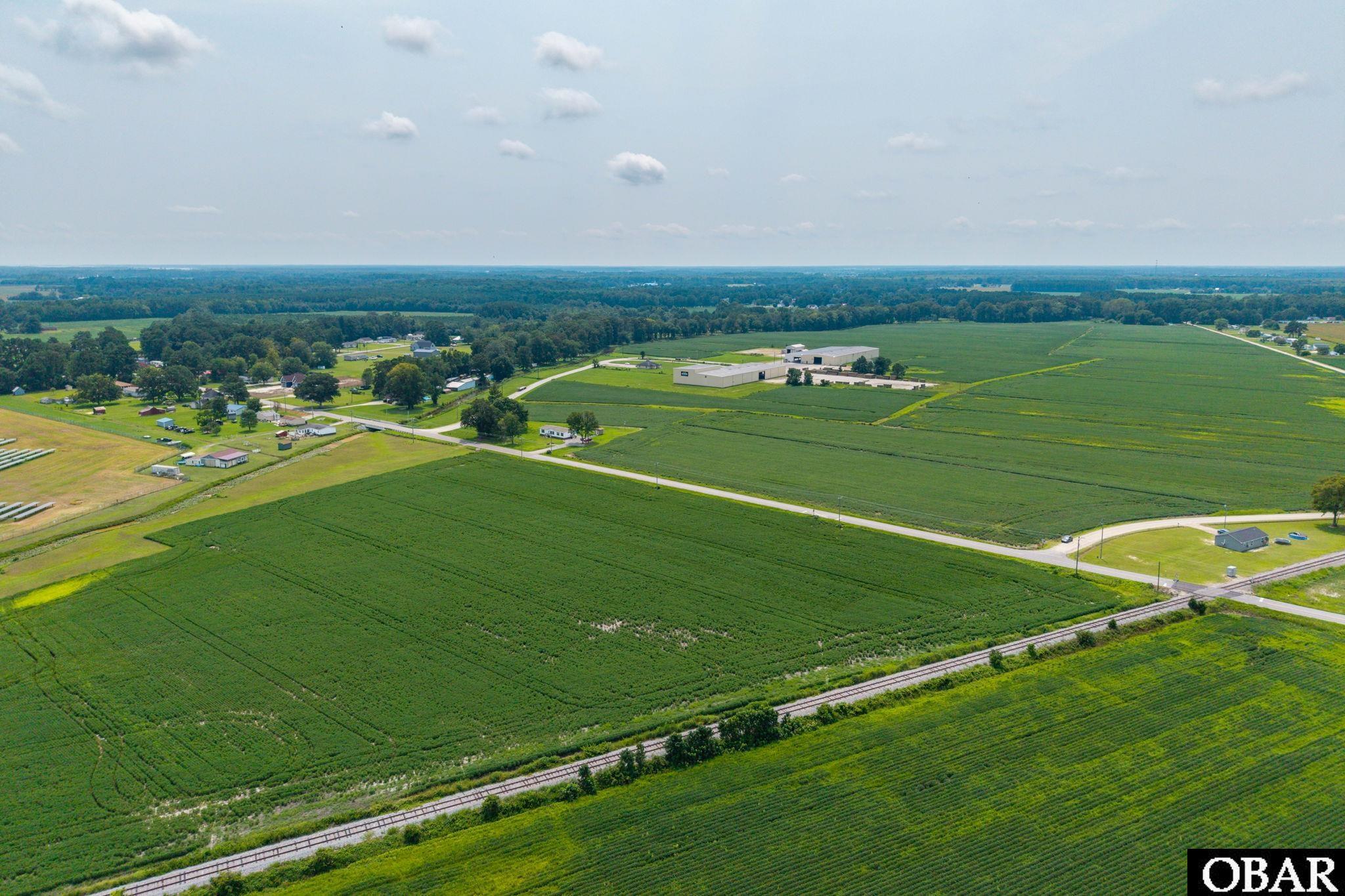 Aerial farmland with railroad tracks in the foreground and a road crossing the fields.