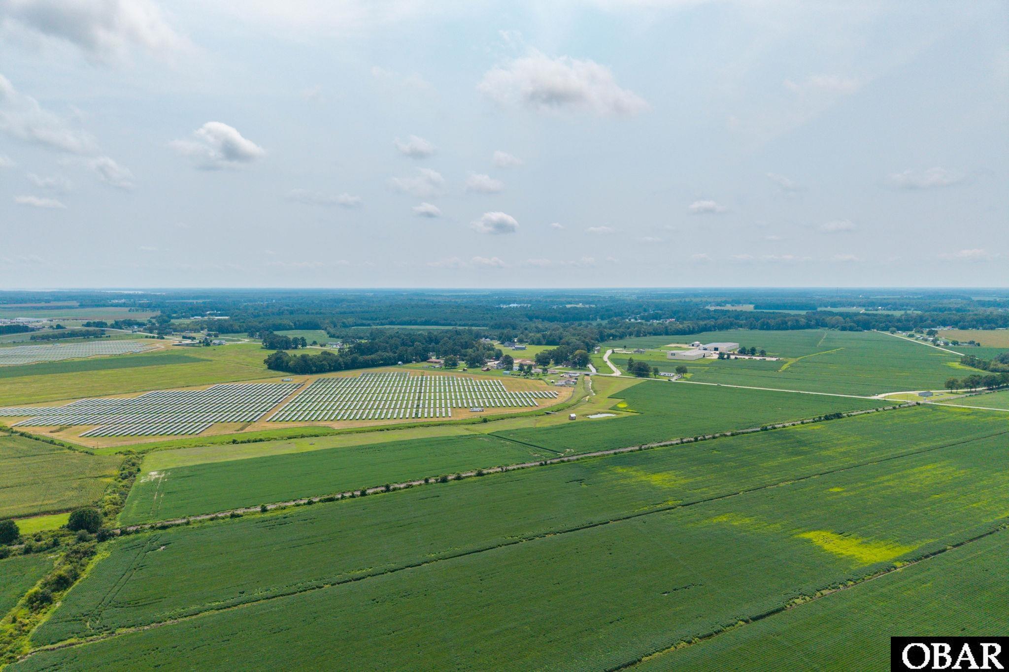 Aerial view of expansive farmland with crop fields and rows of solar panels.