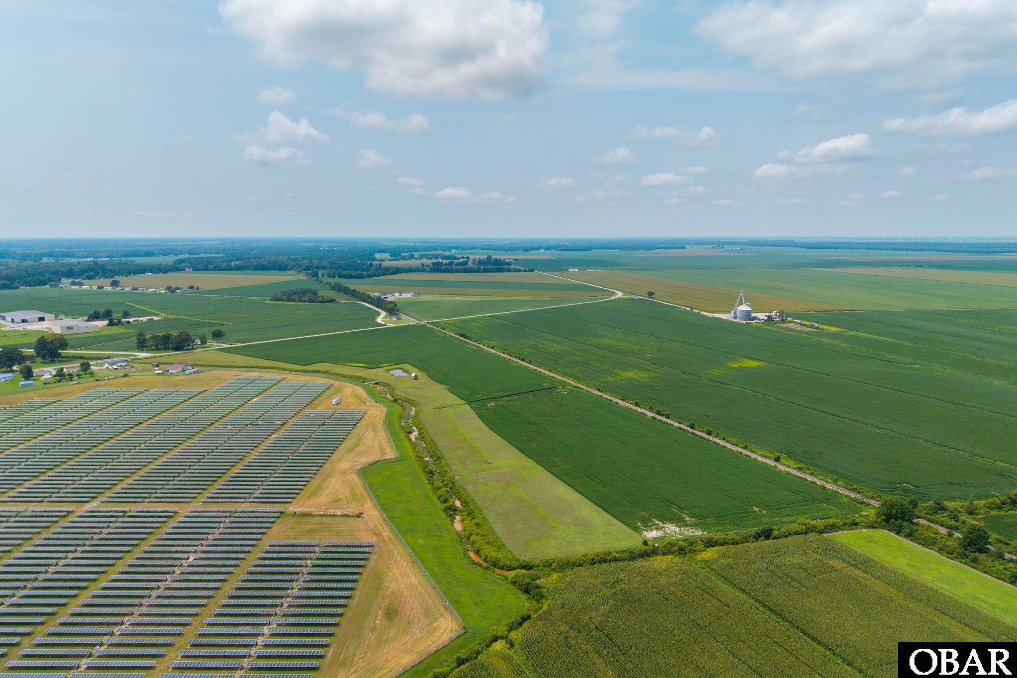 Aerial view of expansive farm fields beside a large solar panel array.