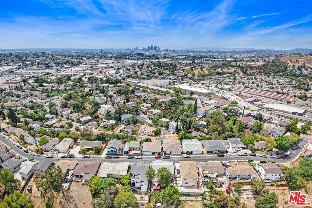 Aerial view of a residential neighborhood with downtown Los Angeles skyline in the distance.
