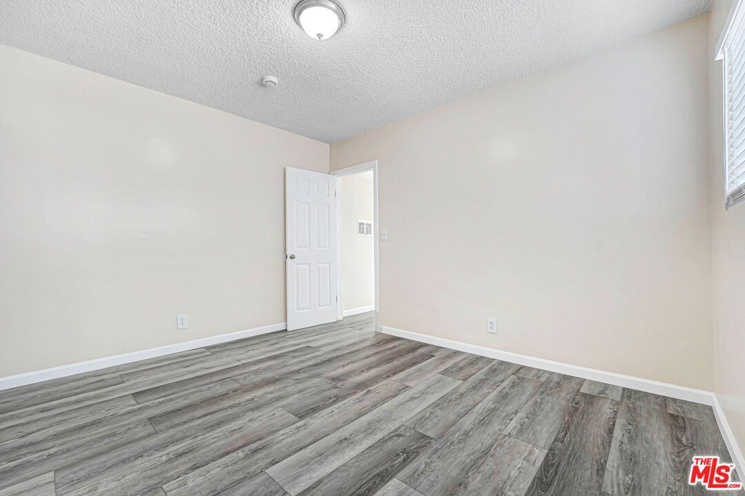 Empty room with gray plank flooring, light walls, and an open door.