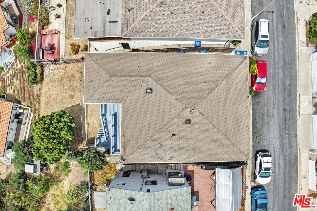 Aerial view of a shingle-roofed home, backyard patio, neighboring houses and street.