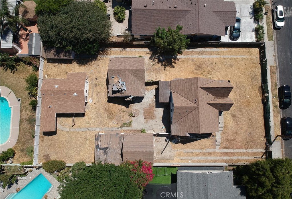 Aerial view of a home and several smaller structures across a large, dry fenced yard.
