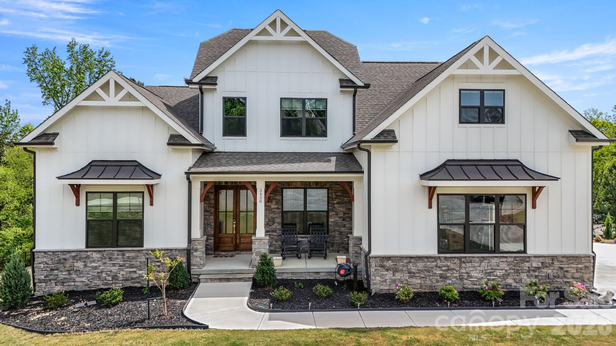 White two-story house with prominent gables, stone veneer, and a covered front porch.