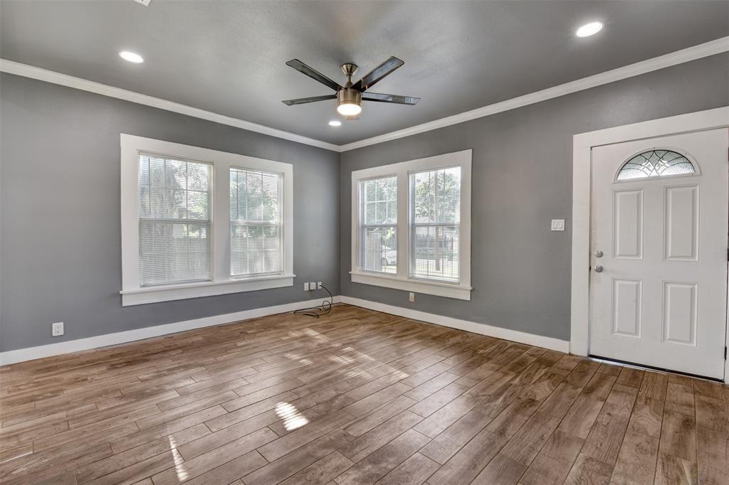 Empty living room with wood-look tile floors, gray walls, and a ceiling fan.