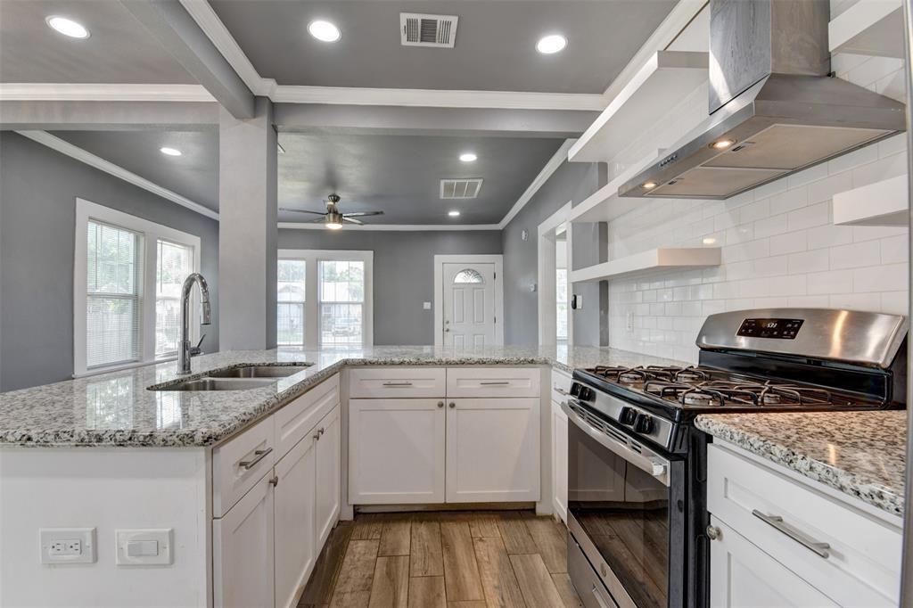 Kitchen with granite counters, white cabinetry, stainless steel range, and an open view into the living area.